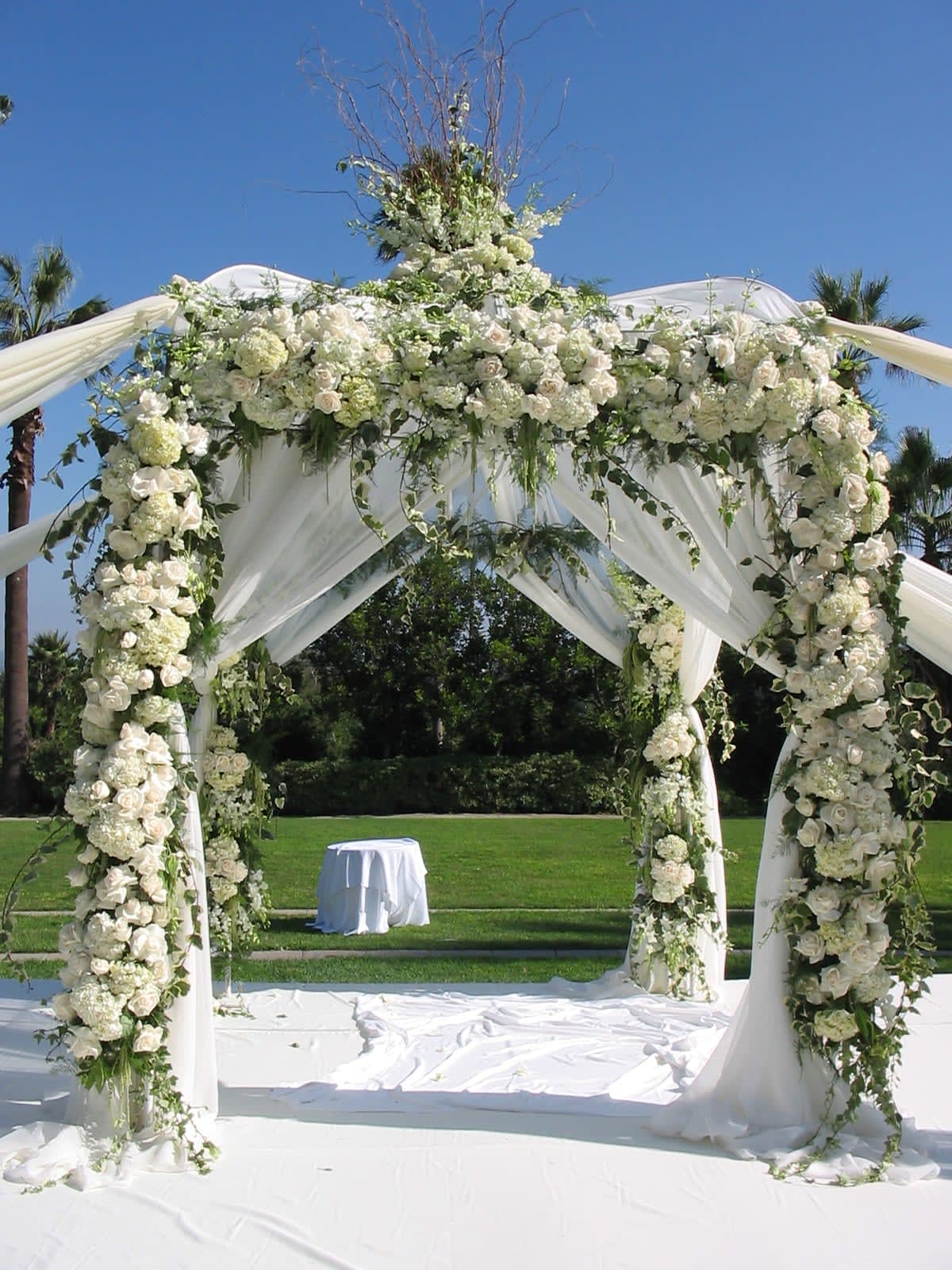 White floral wedding arch draped with fabric outdoors