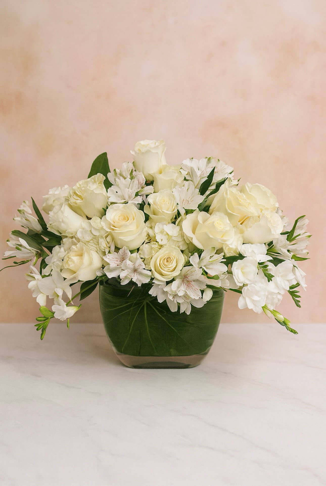 White roses and alstroemeria arranged in a green glass vase
