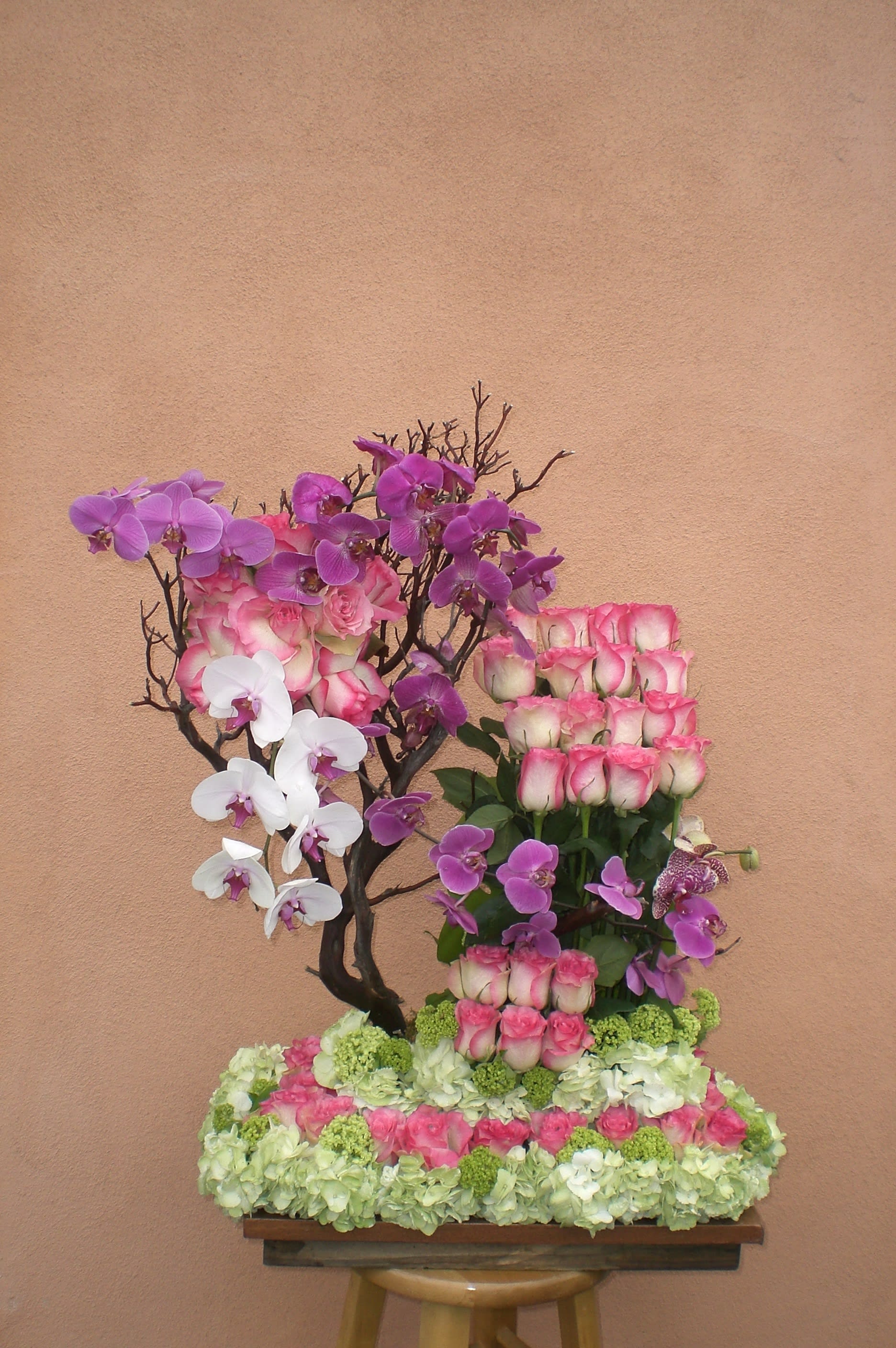 Pink roses and purple orchids arranged on a floral base