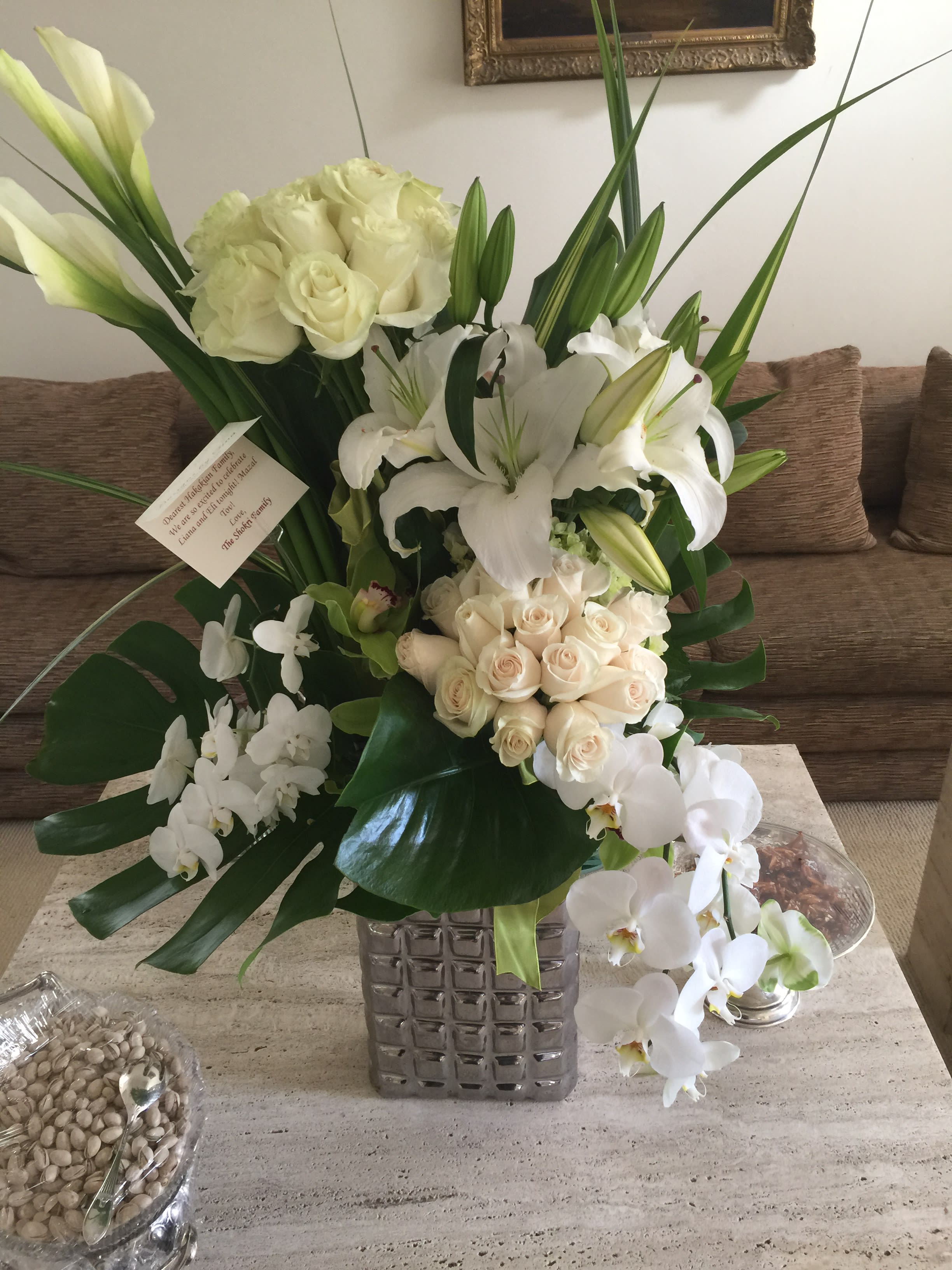 White roses, lilies, and orchids arranged in a square glass vase