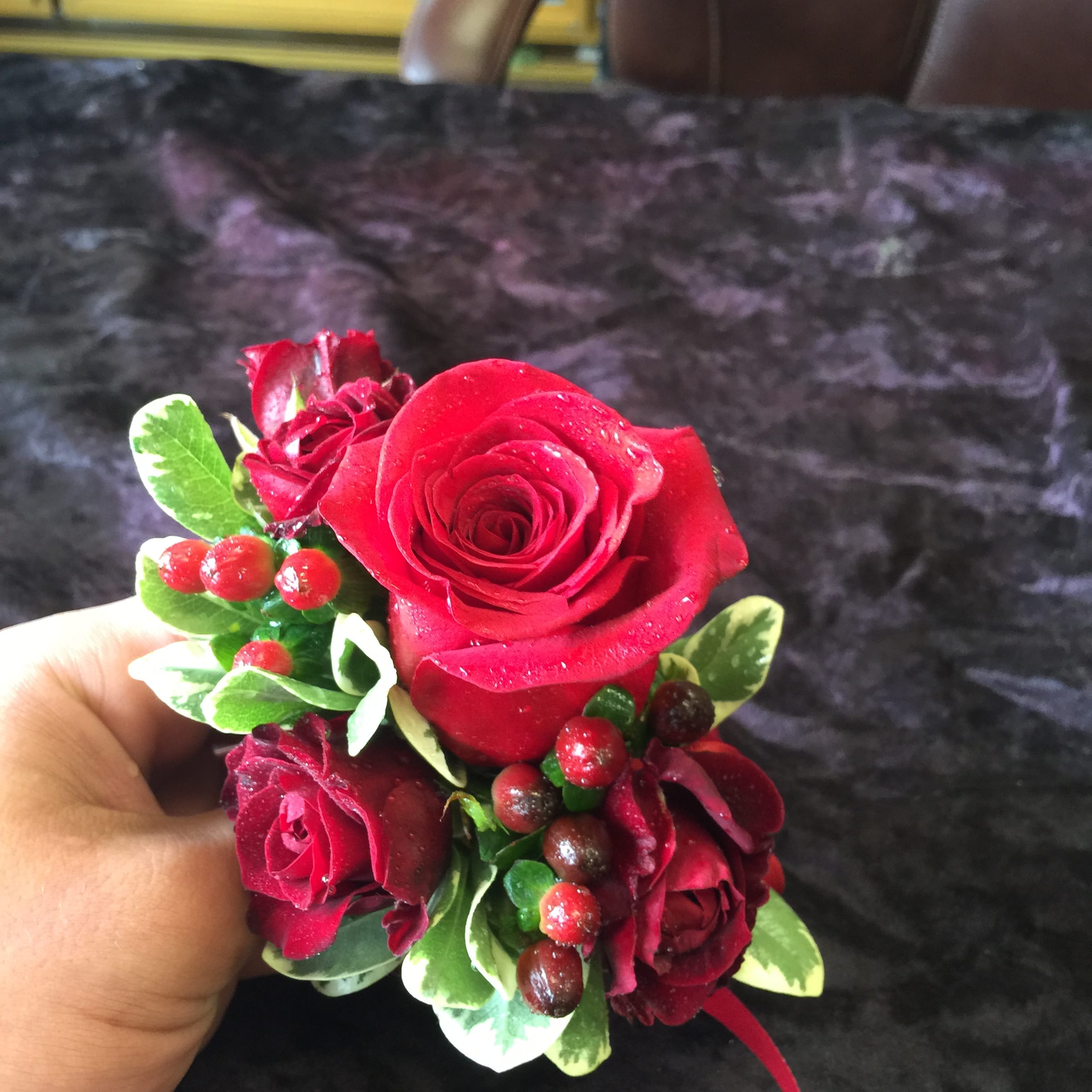 Small bouquet of red roses with berries and variegated leaves