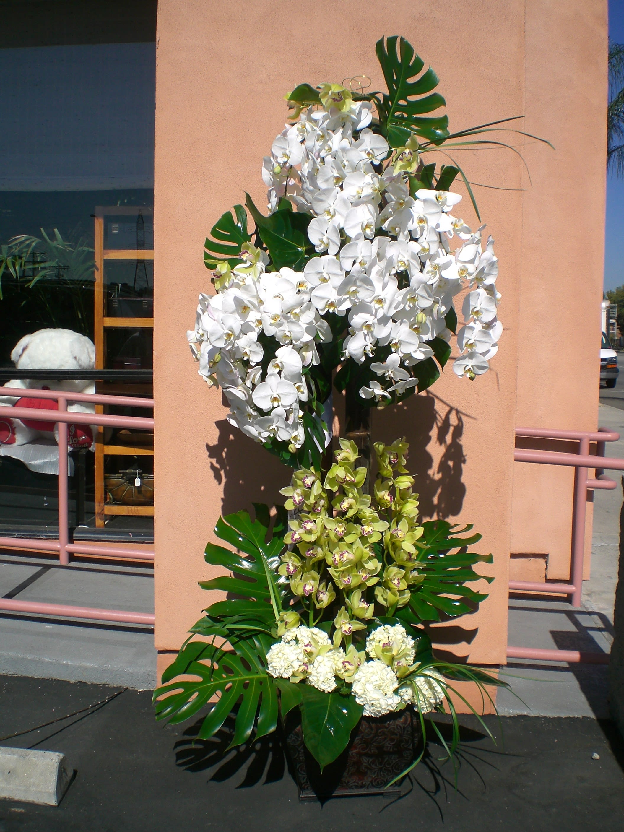 Tall orchid arrangement with white and green blooms in a decorative container