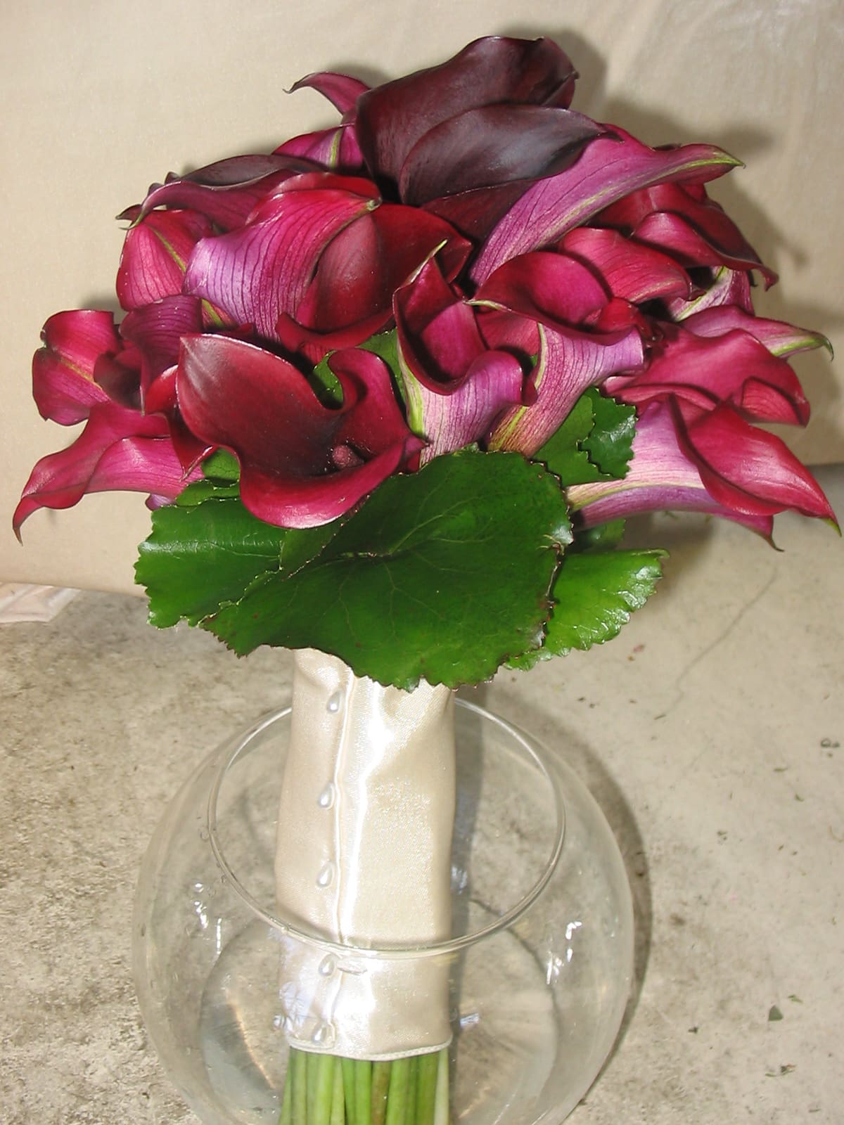 Bouquet of deep pink calla lilies in a glass vase