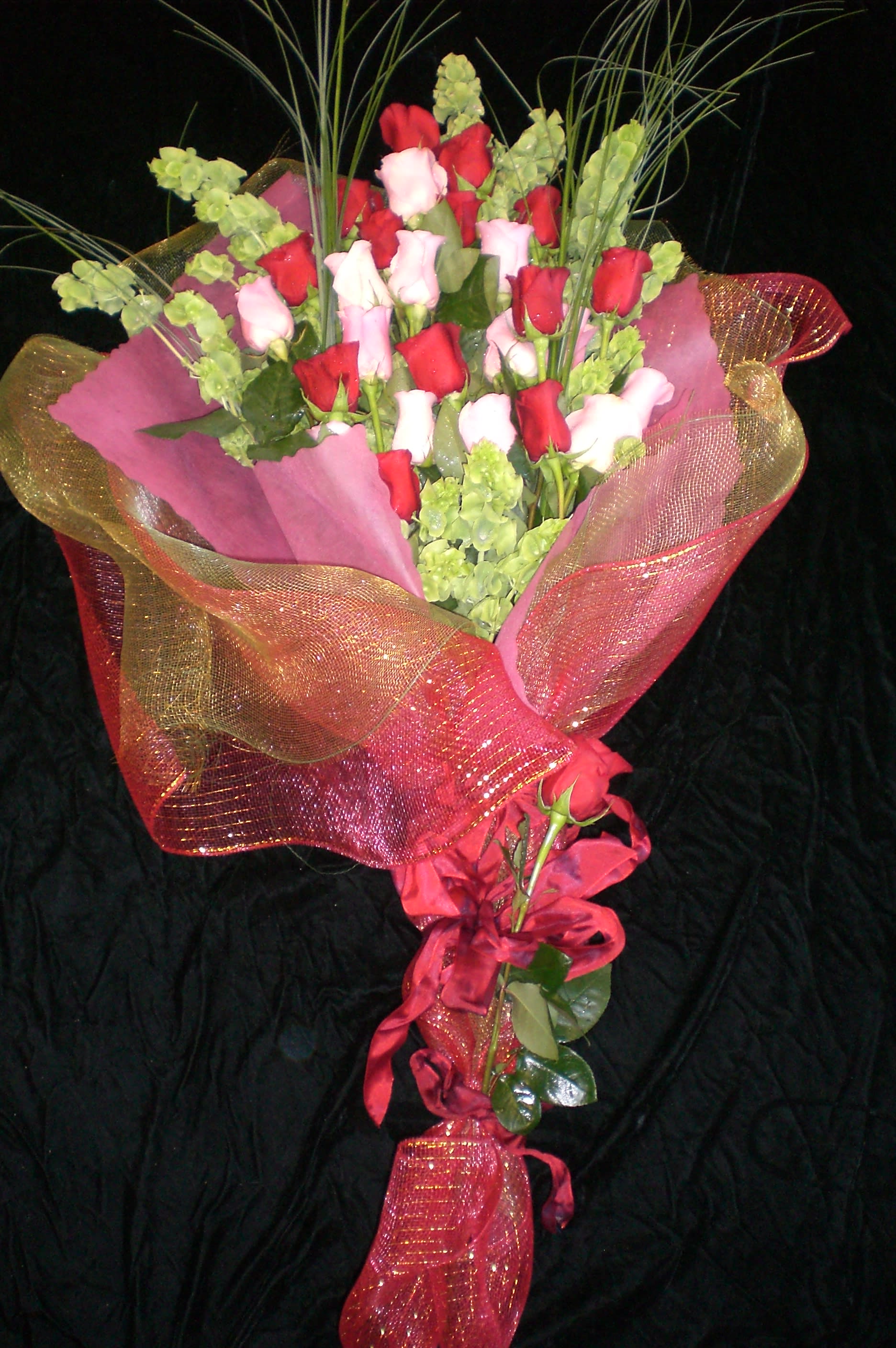 Bouquet of red and pink roses wrapped in pink and gold mesh