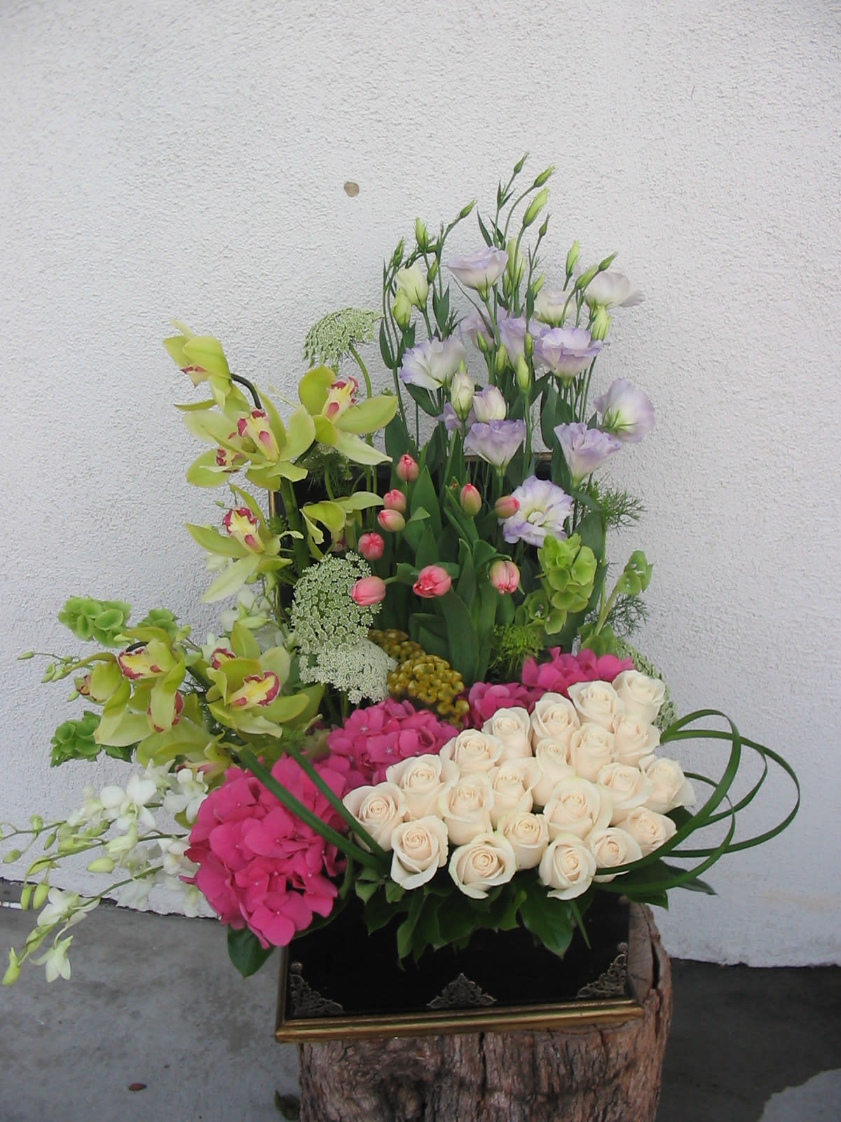 Tall floral arrangement with cream roses, pink hydrangeas, and green orchids