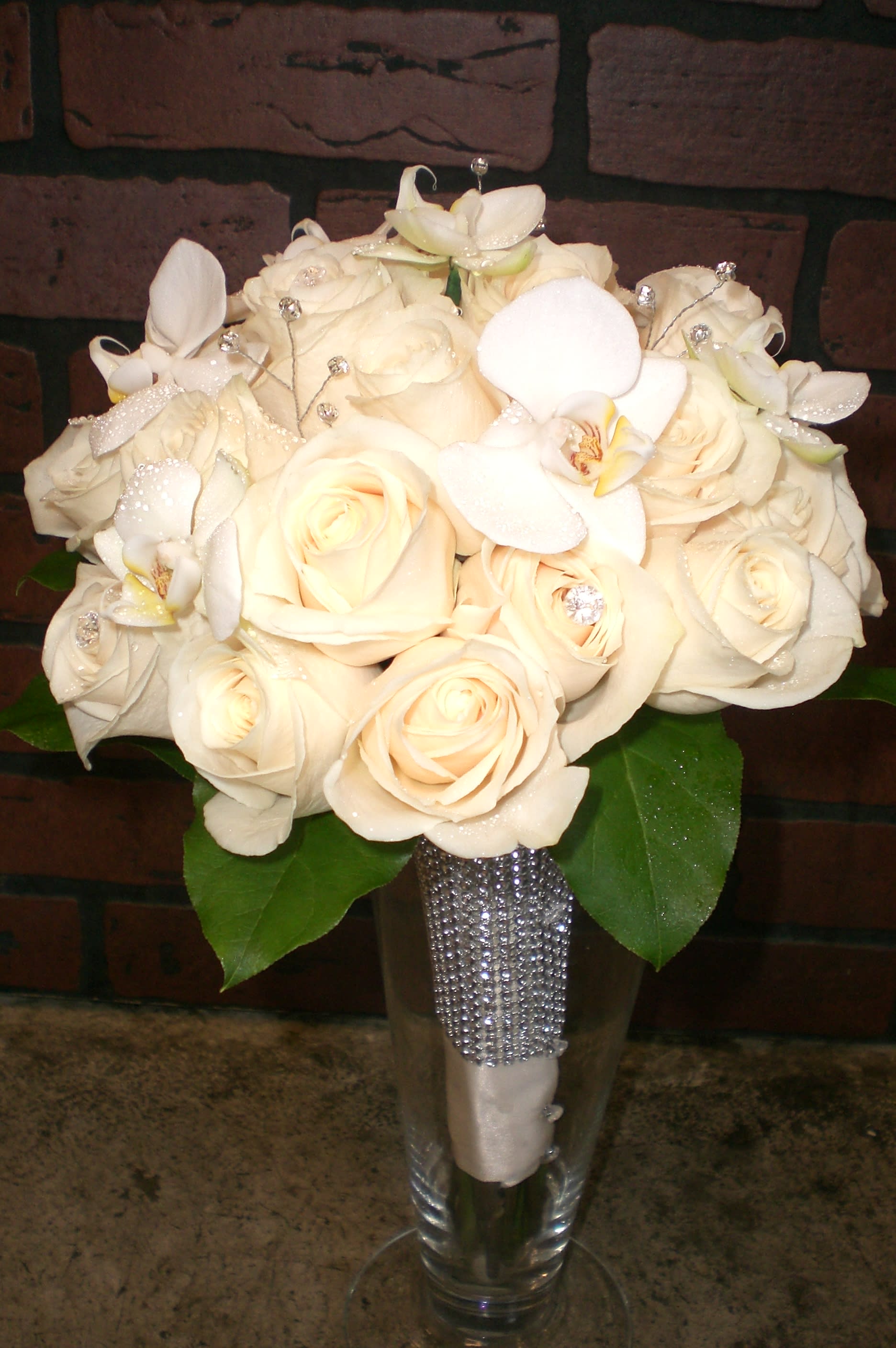 Cream rose bouquet with white orchids in a clear vase