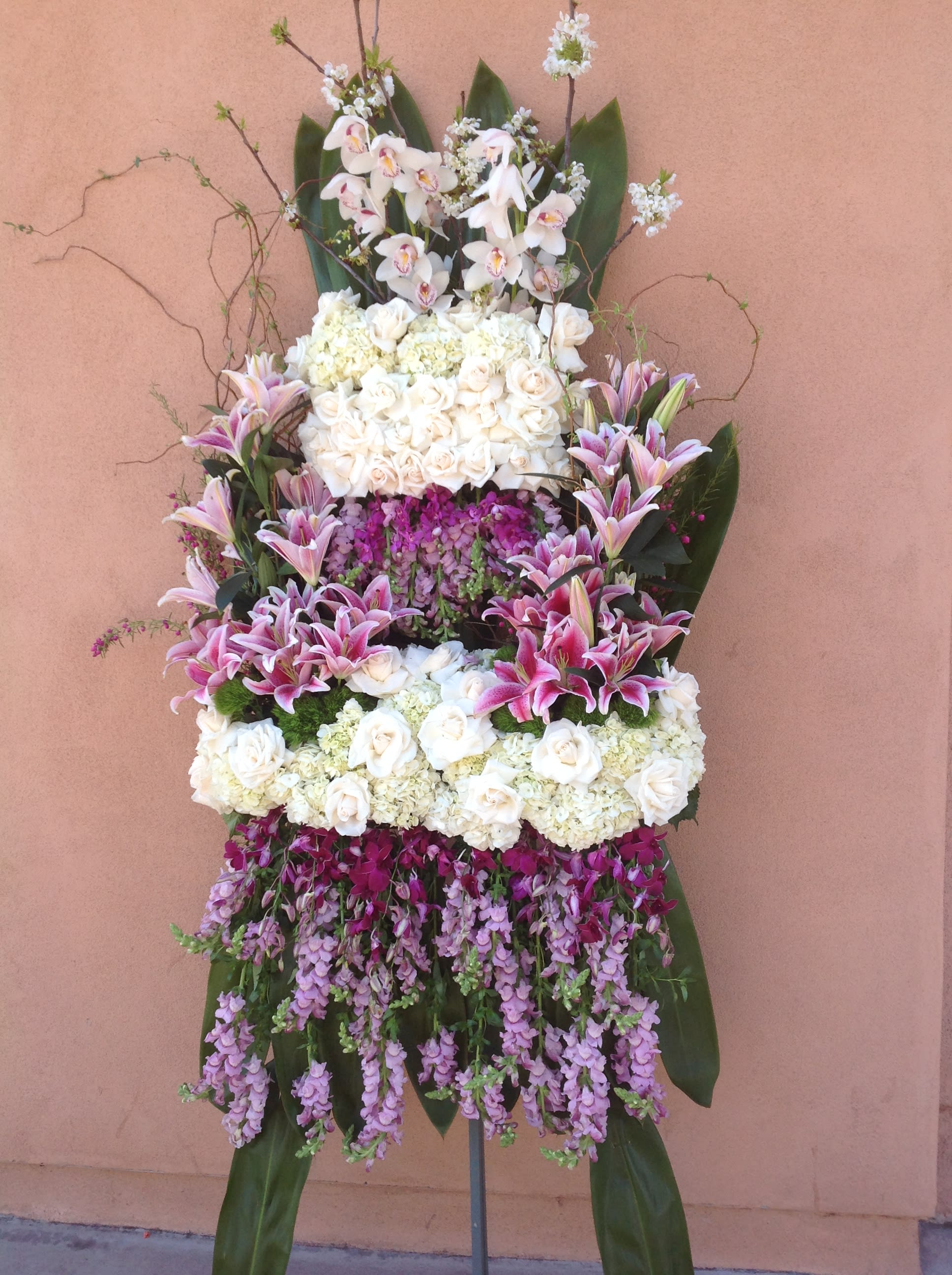 Tall standing floral spray with white roses, orchids, and pink lilies