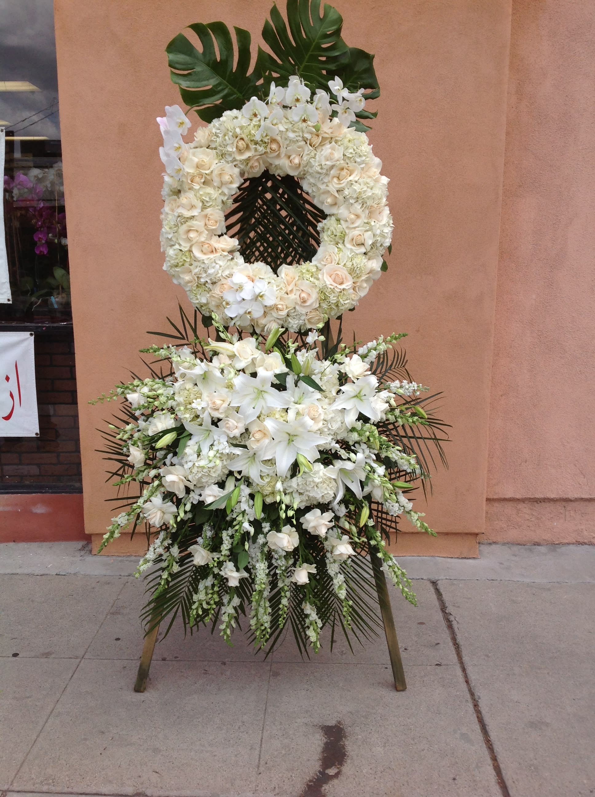 White floral funeral wreath and standing spray on an easel
