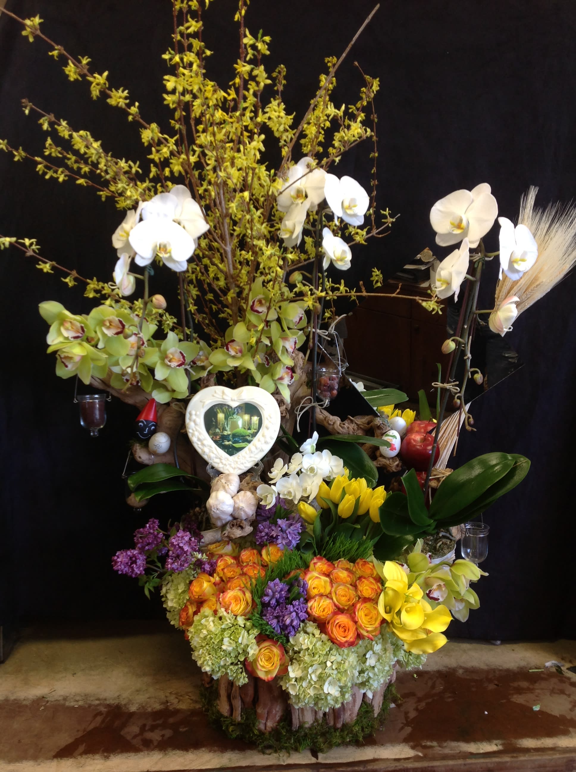 Large floral arrangement with orchids, roses, and tulips in a decorative base