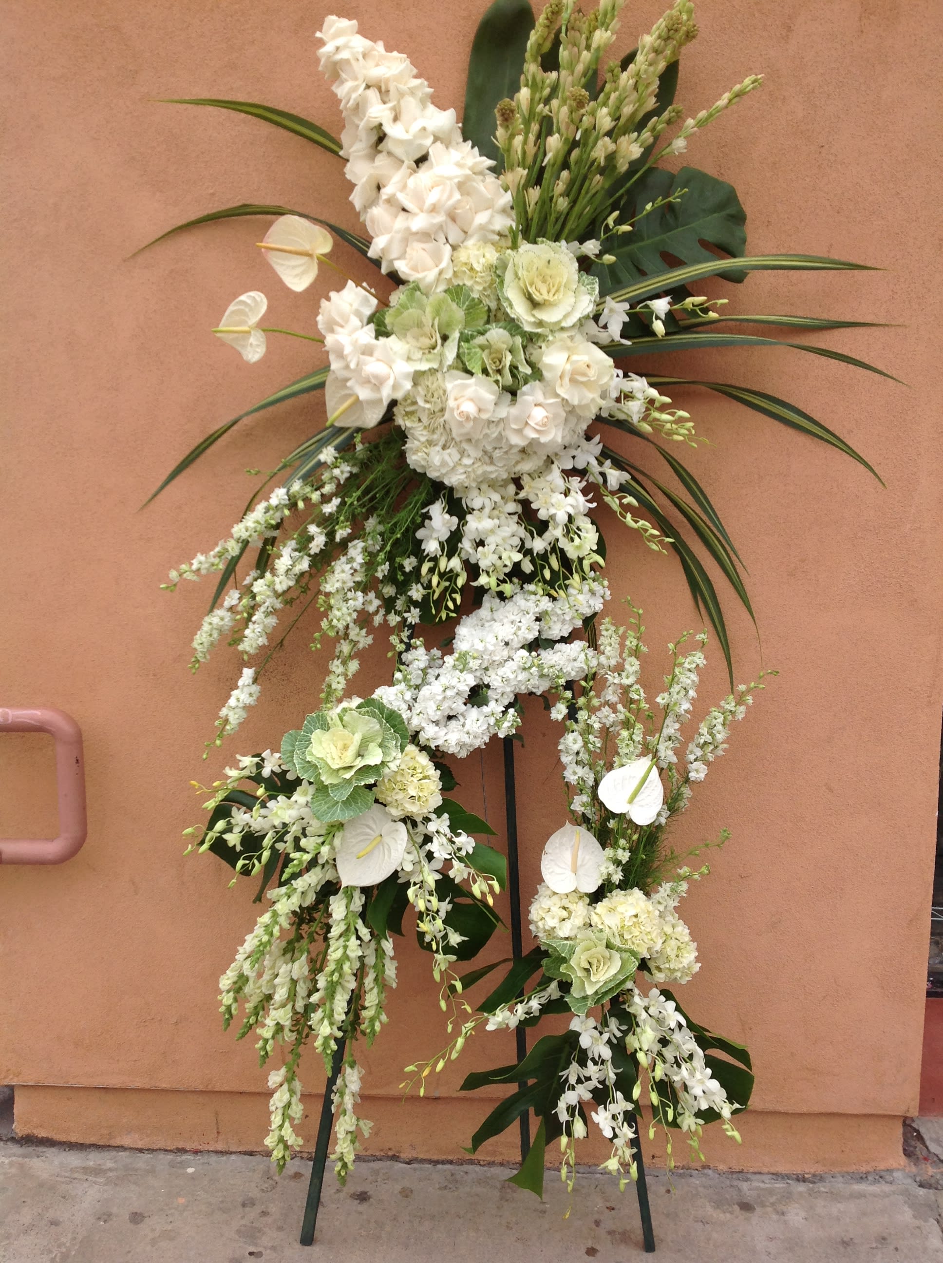 Tall white floral standing arrangement on a metal easel