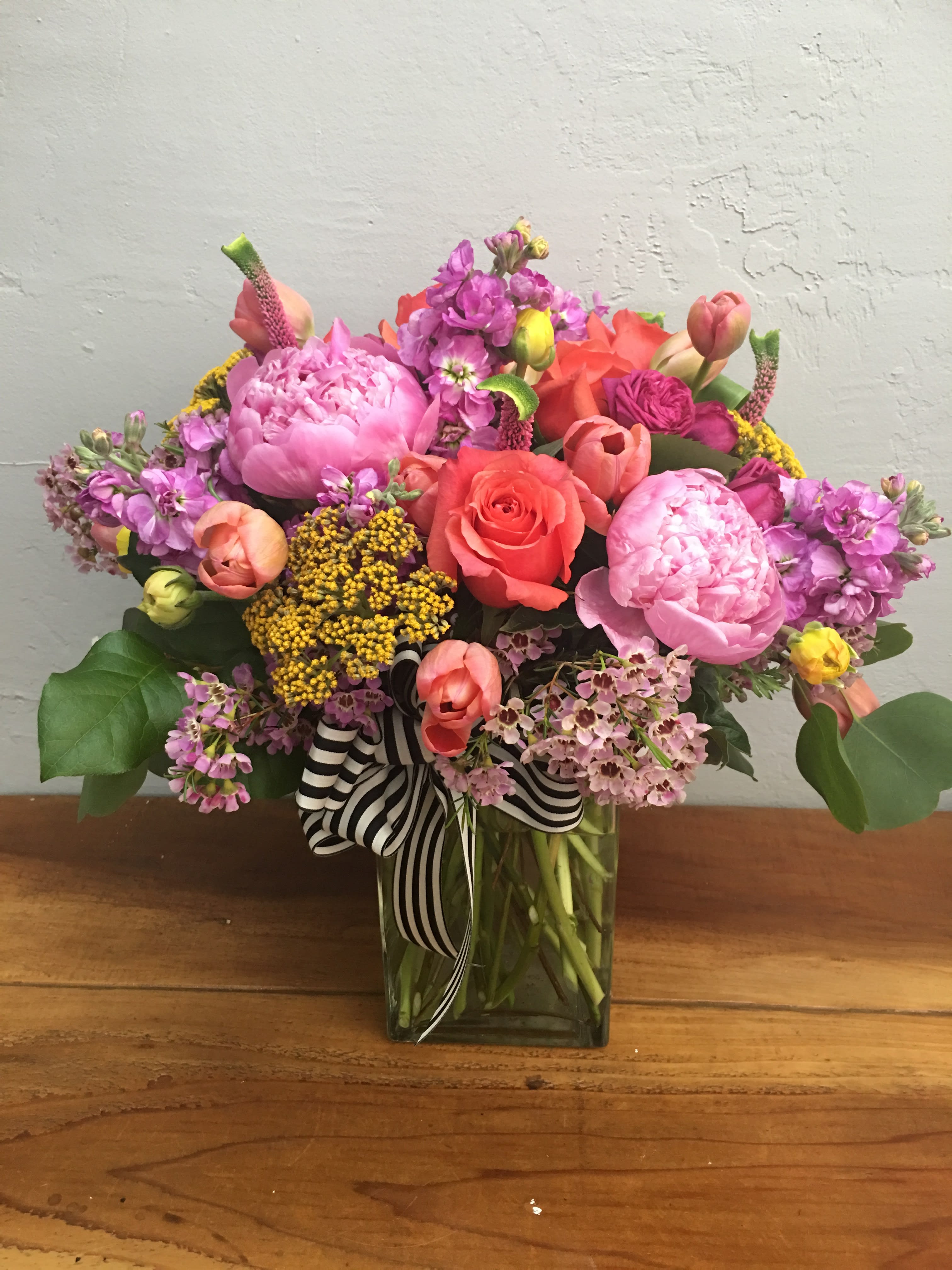 Colorful mixed bouquet in a glass vase with a striped ribbon