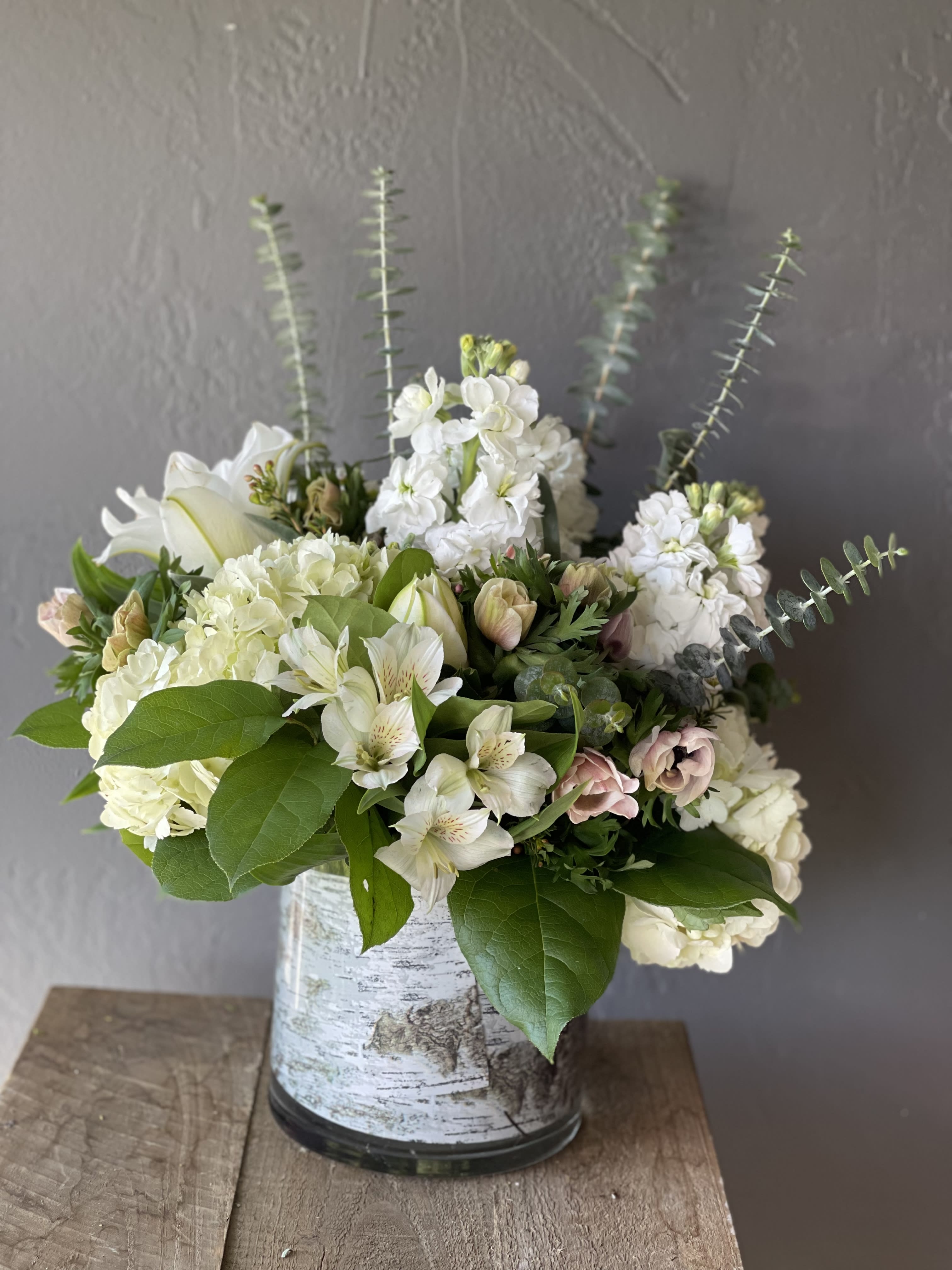 White floral arrangement in a birch-pattern vase with tall stems