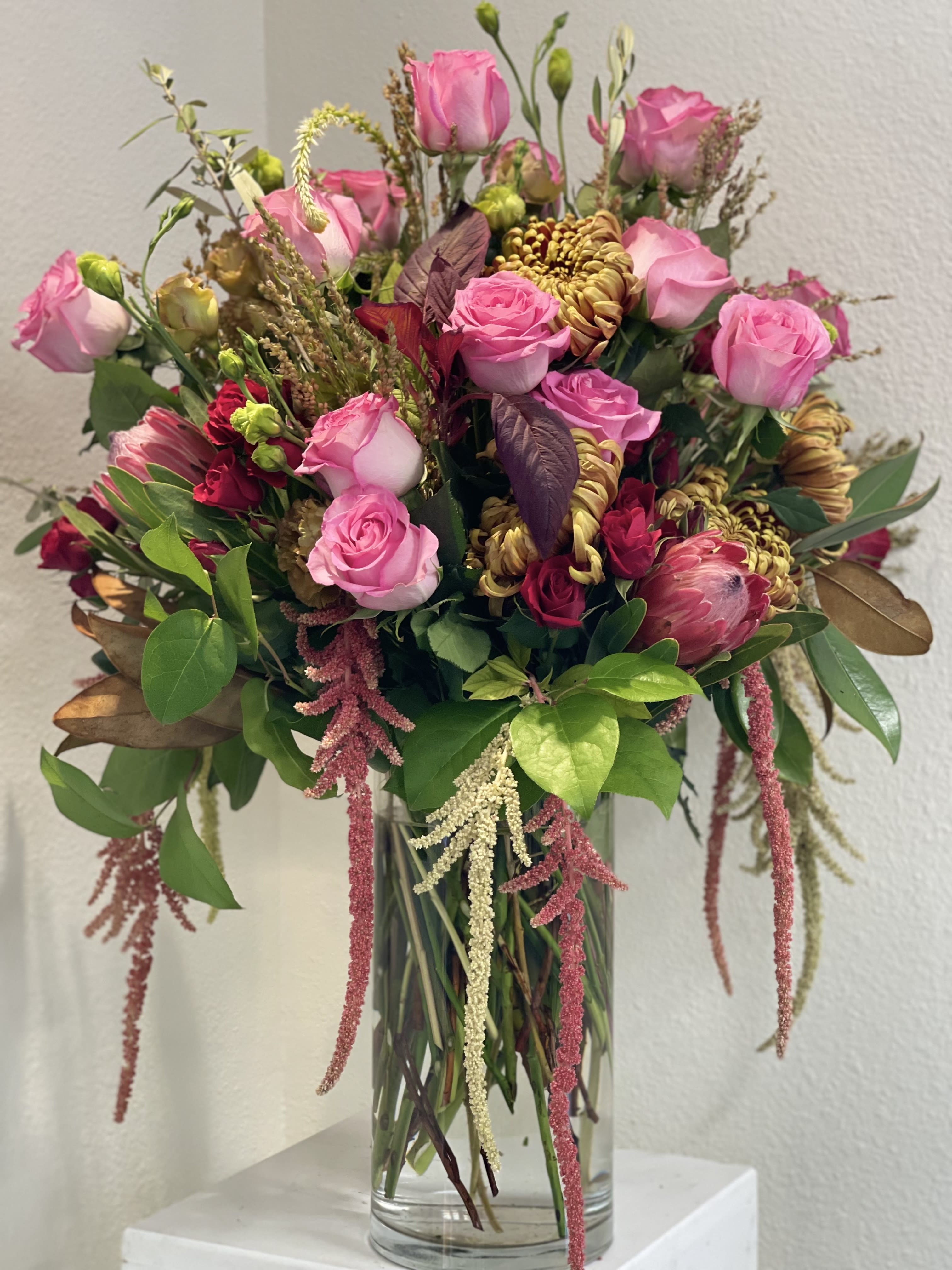 Pink roses and mixed blooms arranged in a clear glass vase