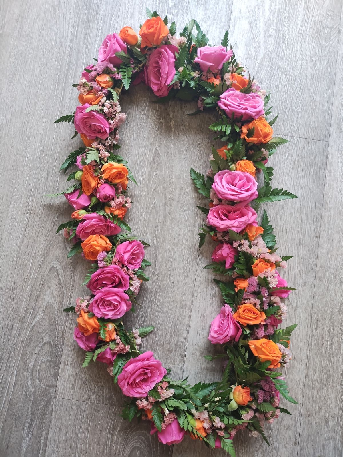 Floral wreath of pink and orange roses on a wood floor
