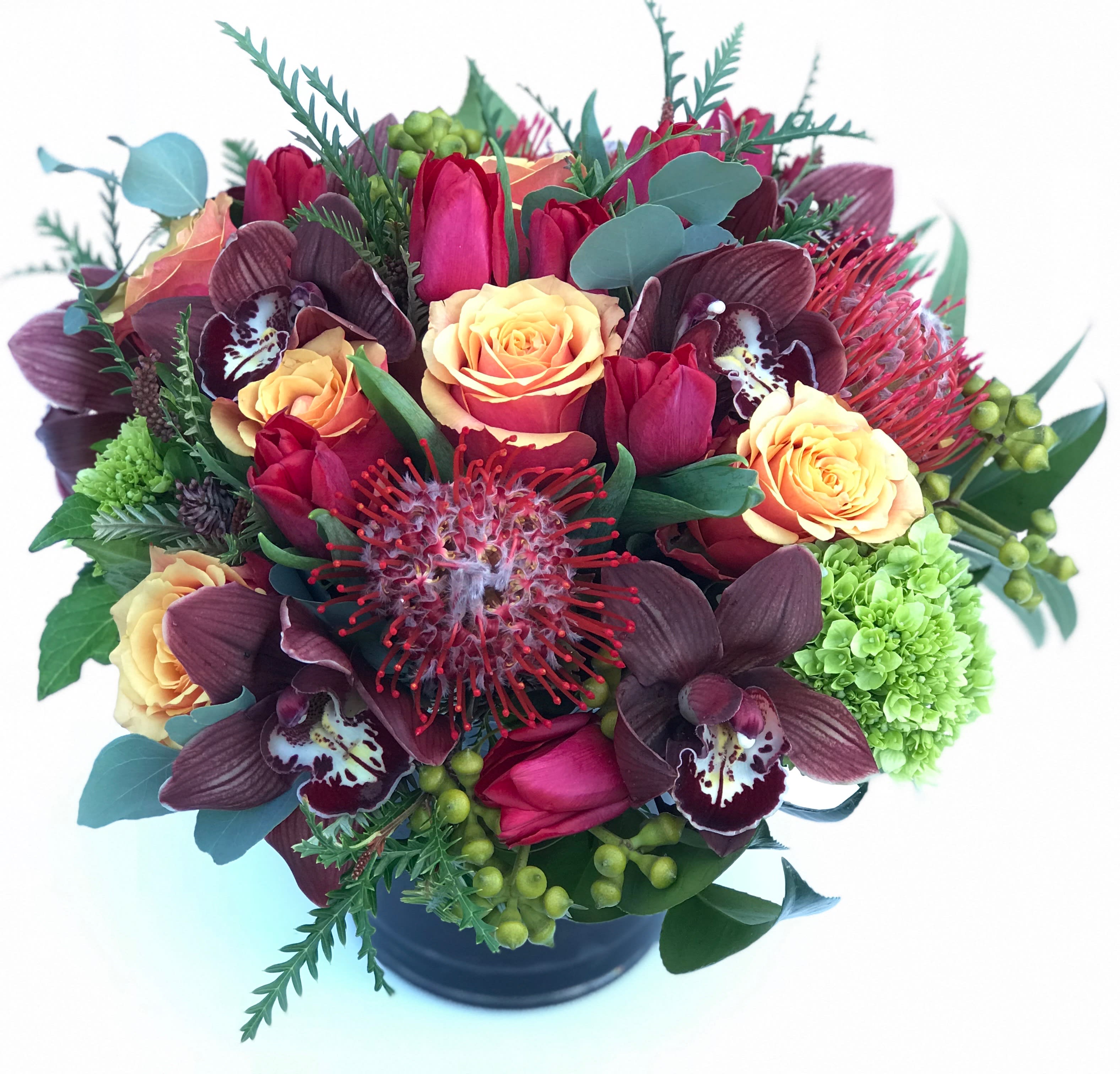 Bouquet of red tulips, peach roses, and dark orchids in a black vase