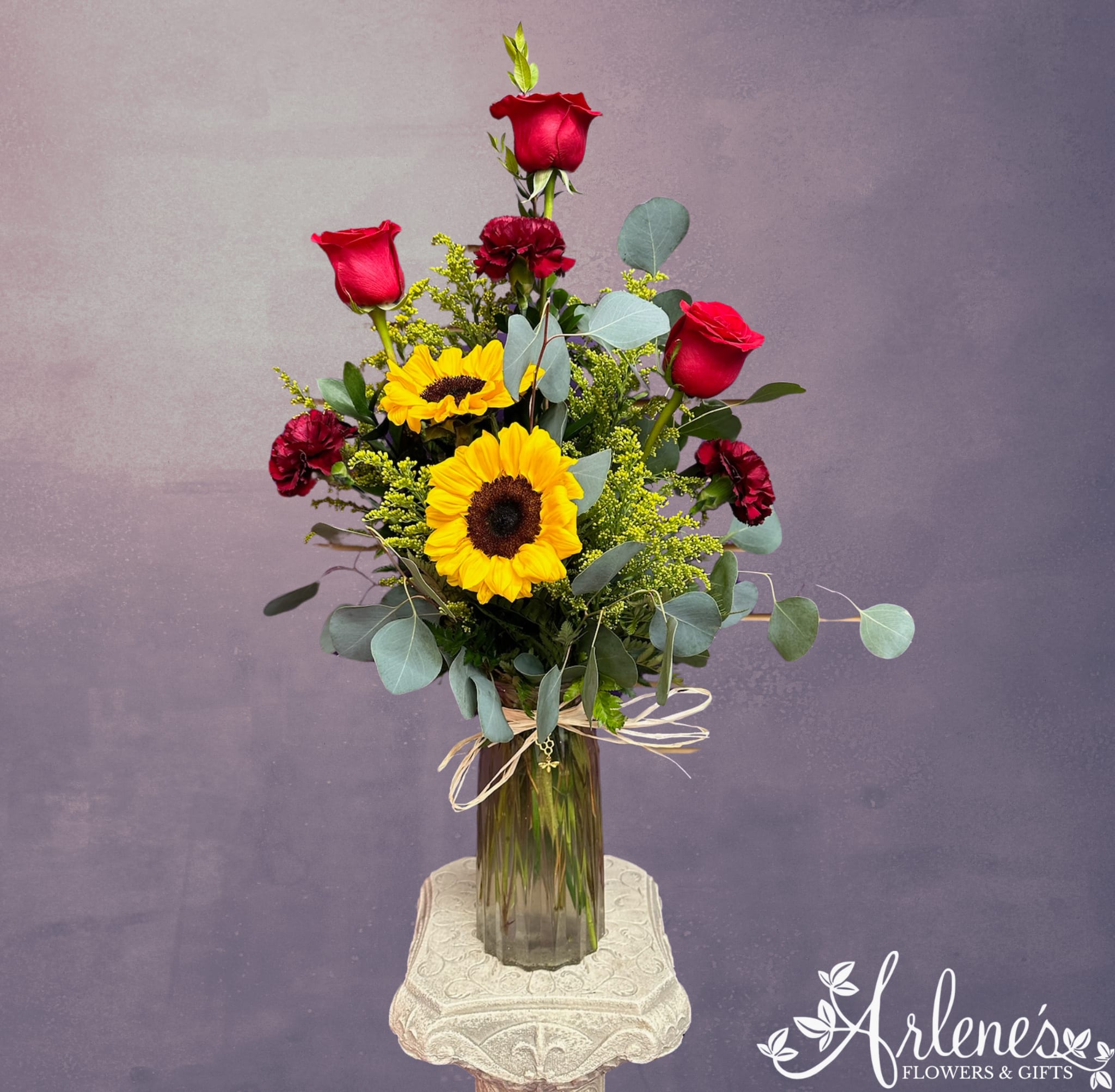 Tall bouquet of red roses and yellow sunflowers in a glass vase