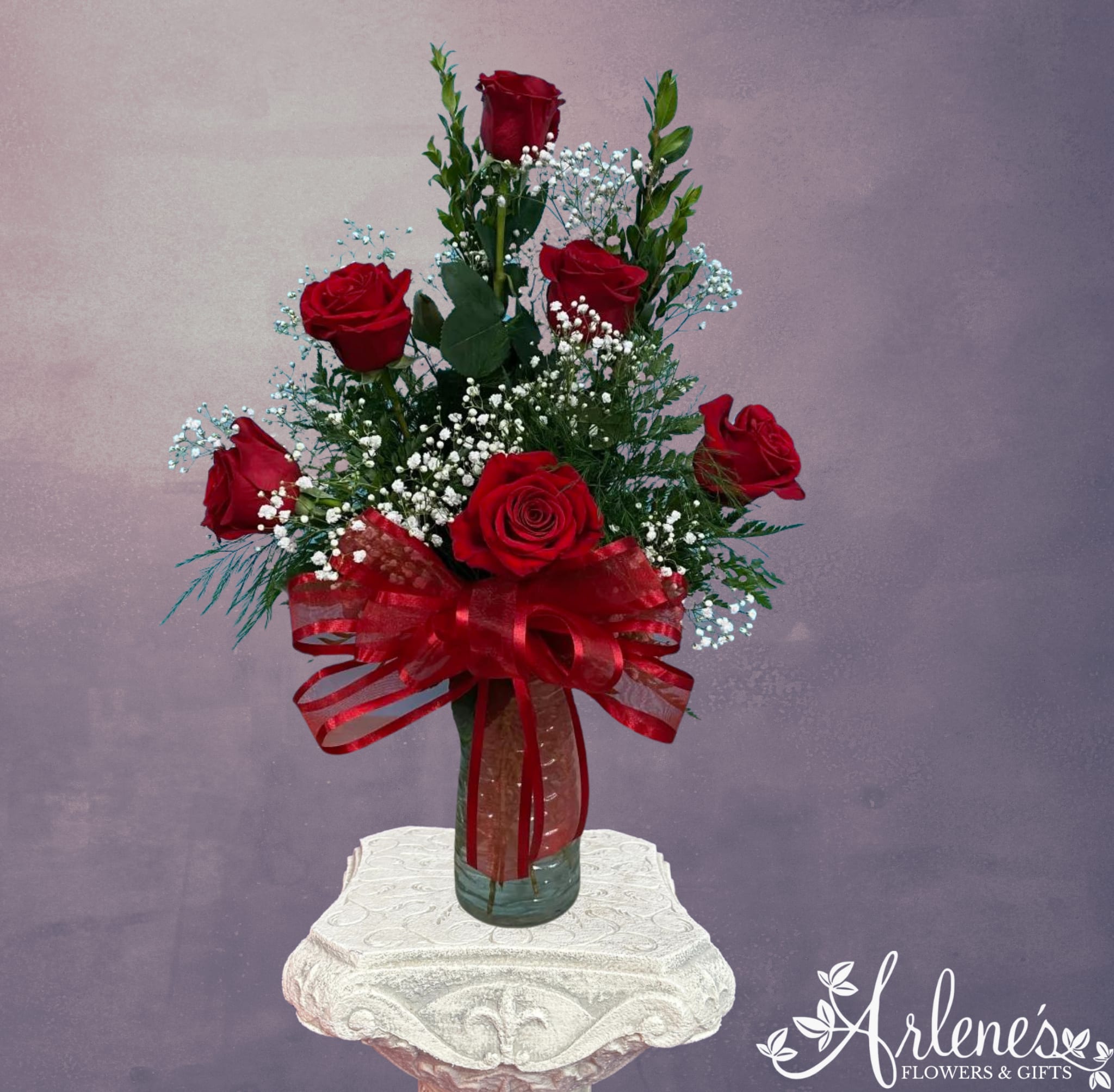 Red roses in a glass vase with a red ribbon bow