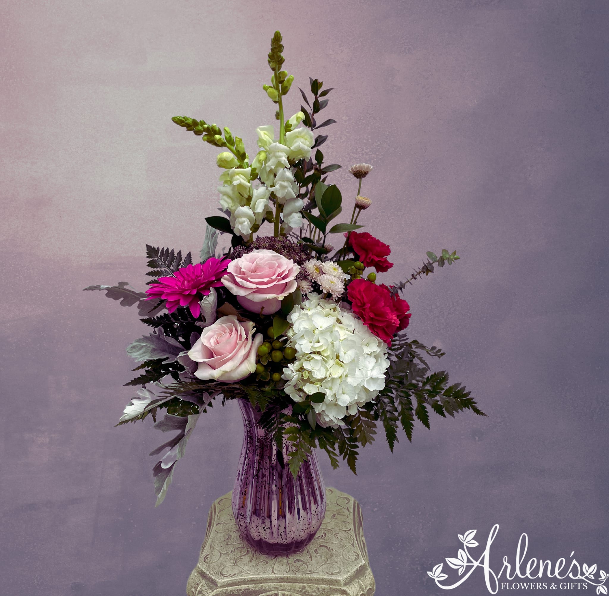 Mixed bouquet in a purple glass vase with pink, white, and magenta flowers