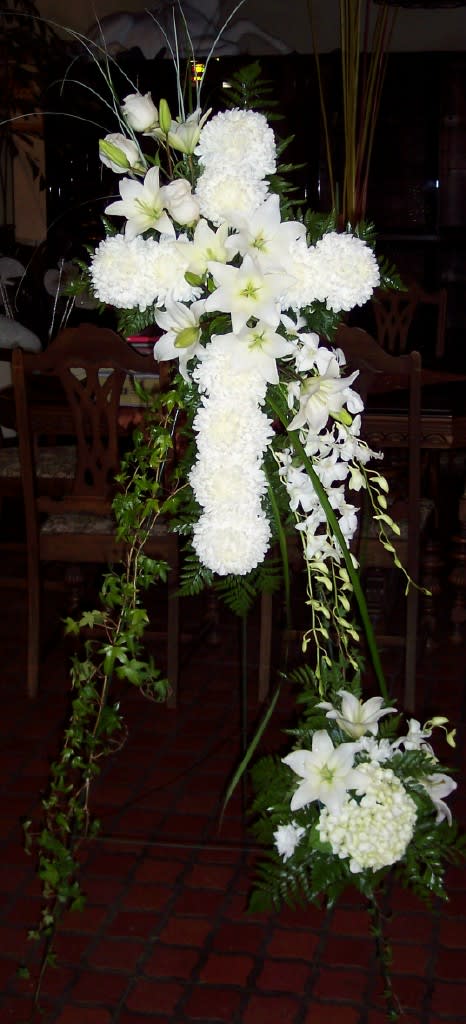 White floral cross arrangement with lilies and pompons on a stand