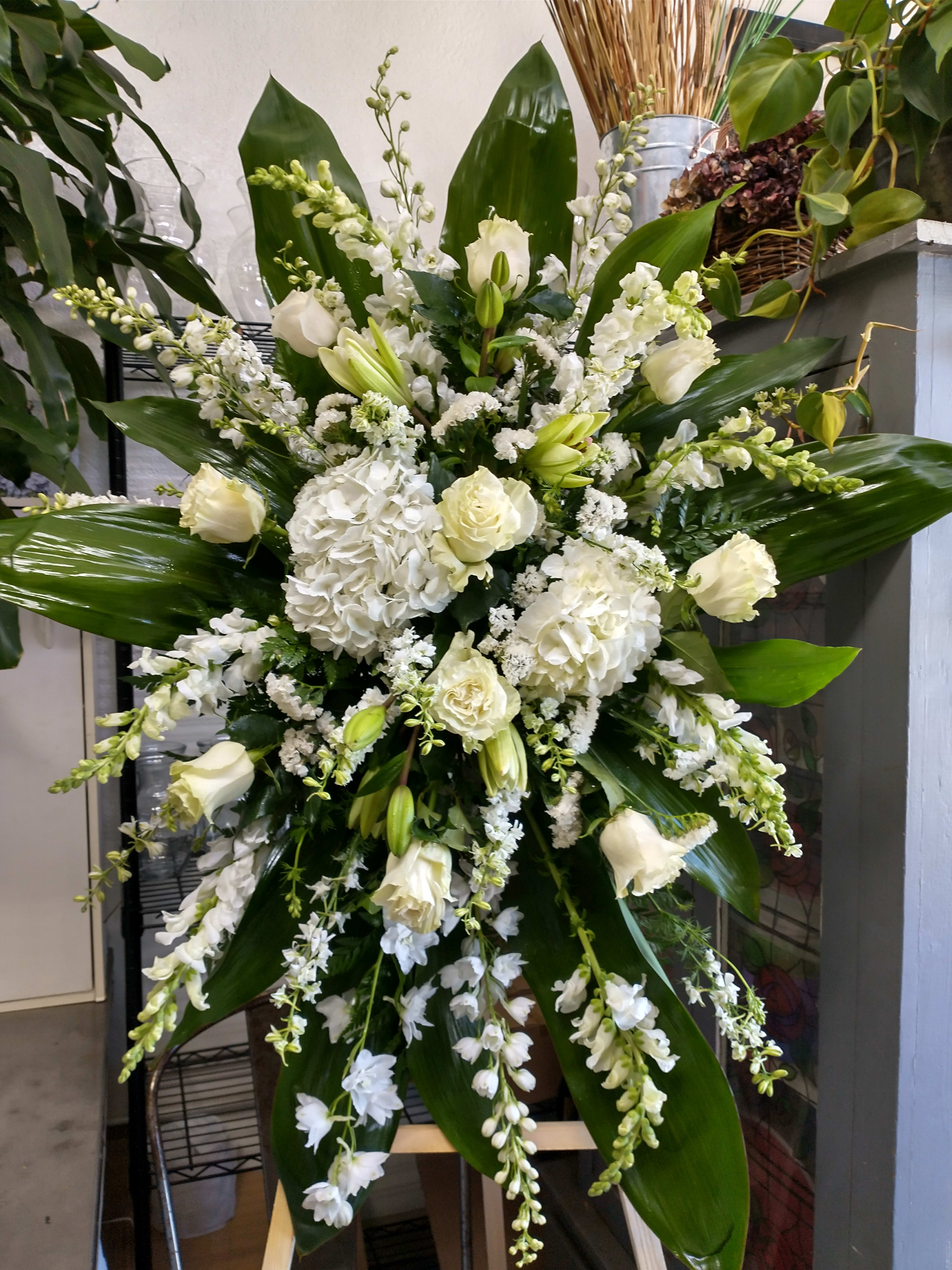 Large white floral standing spray with lilies, roses, and hydrangeas