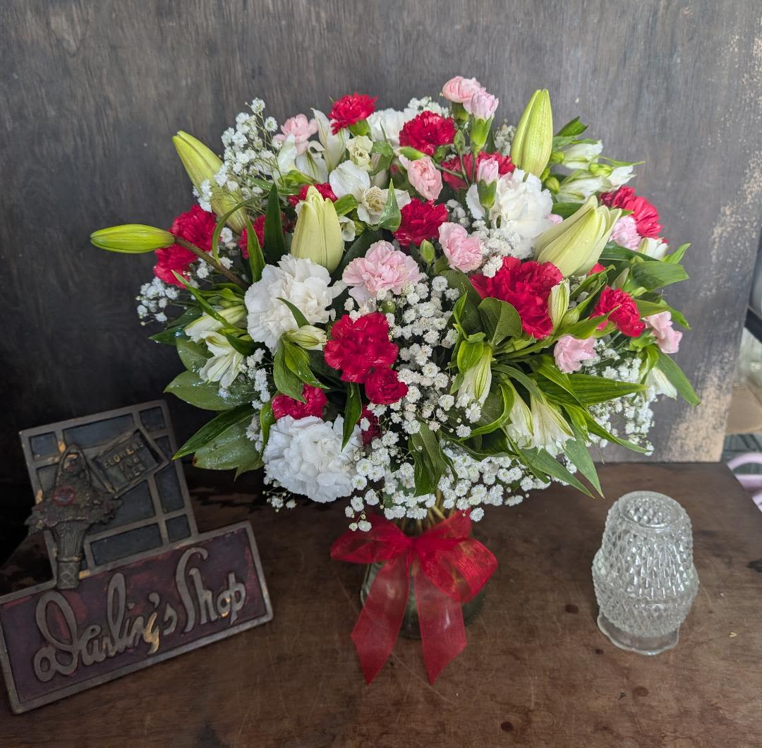 Bouquet of pink, white, and red flowers in a glass vase with a red ribbon