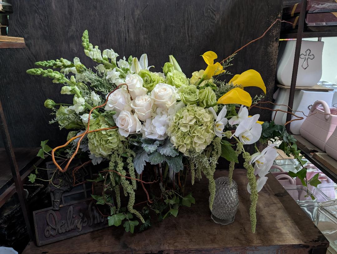 Large floral arrangement with white roses, green hydrangeas, and yellow calla lilies