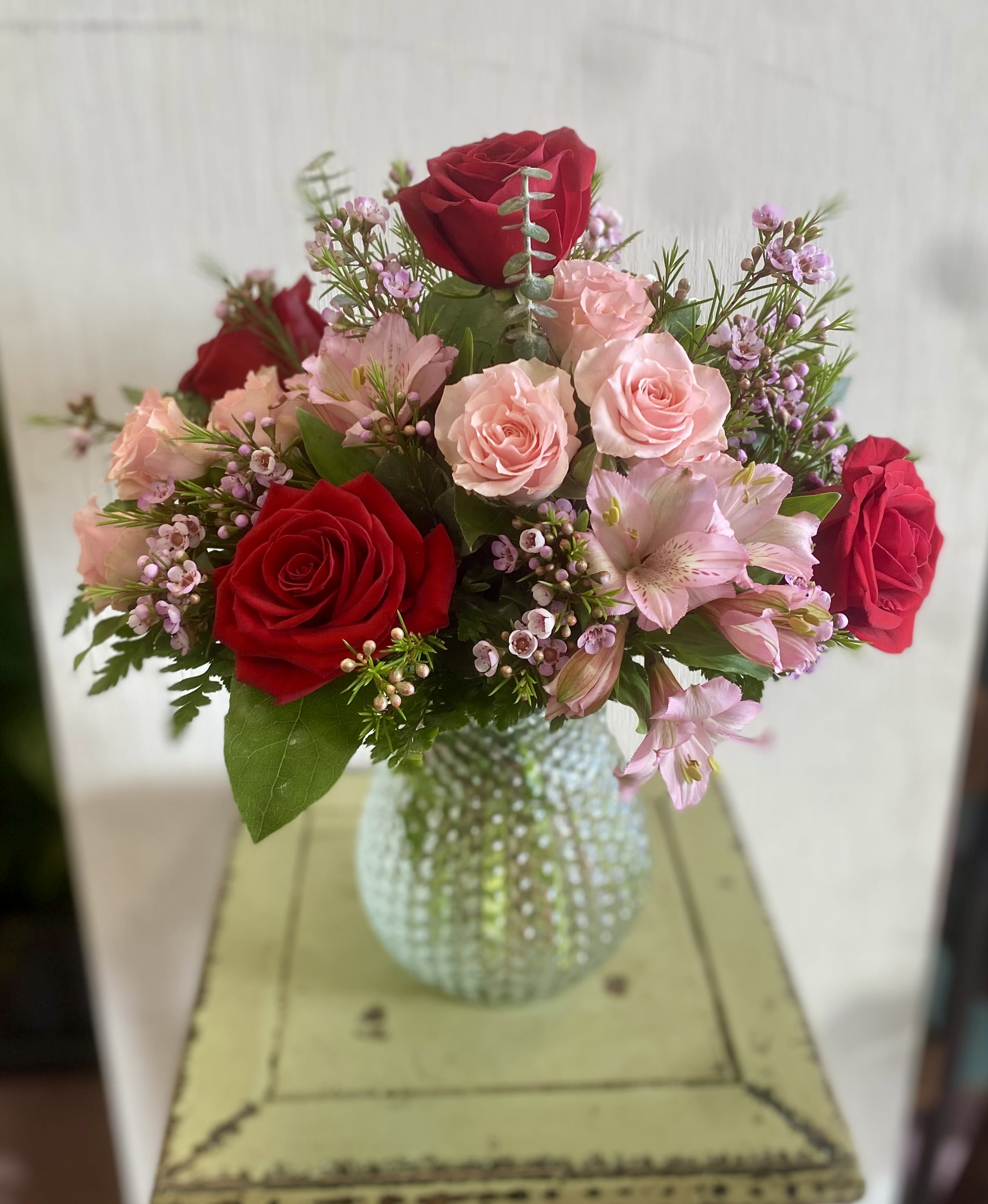 Bouquet of red and pink roses in a textured glass vase