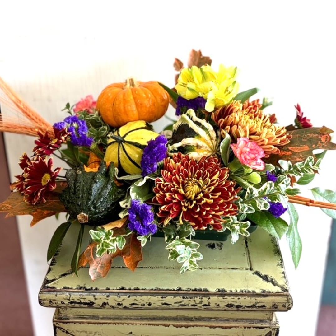 Autumn floral arrangement with pumpkins and chrysanthemums on a pedestal