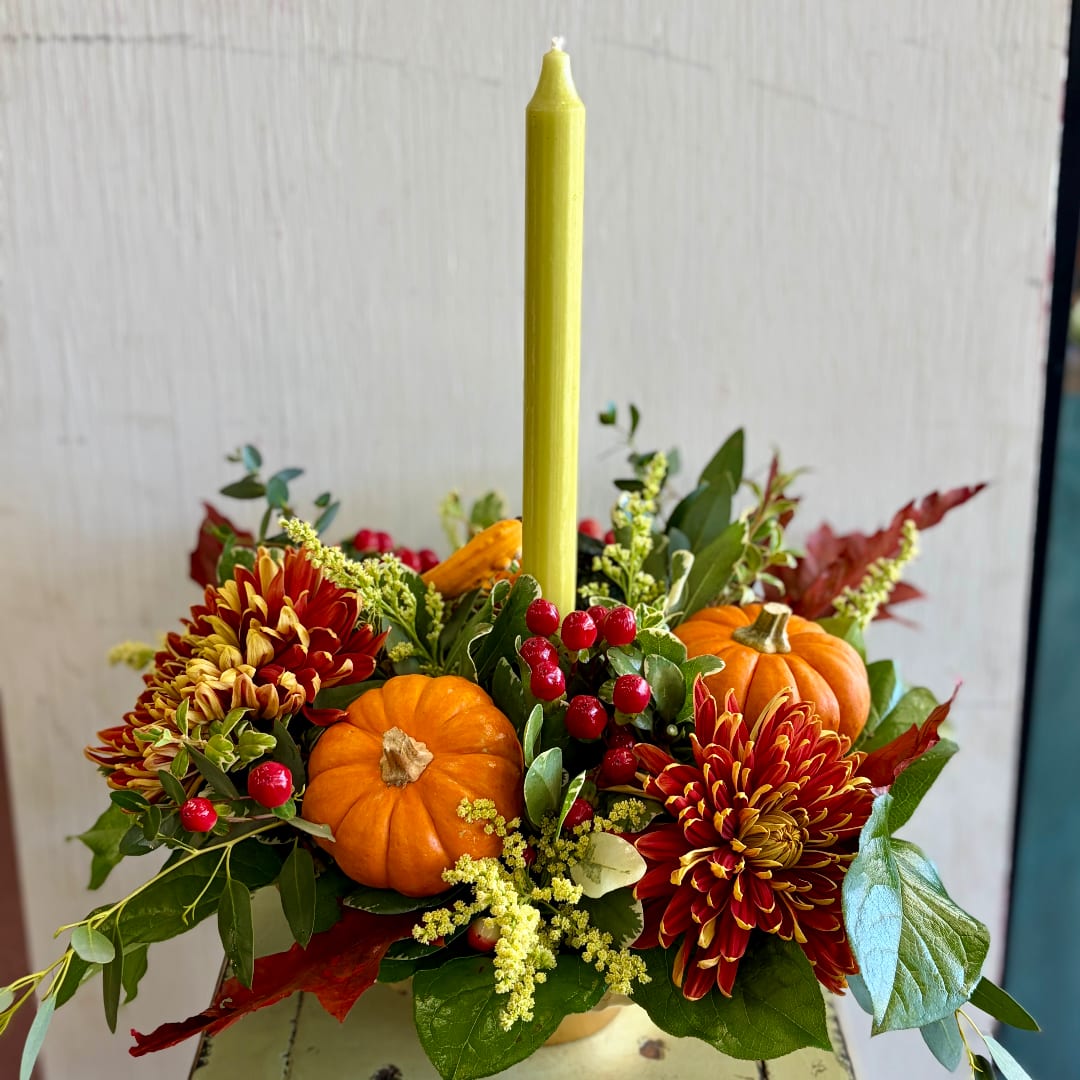 Autumn centerpiece with orange pumpkins, red-yellow mums, and a tall candle