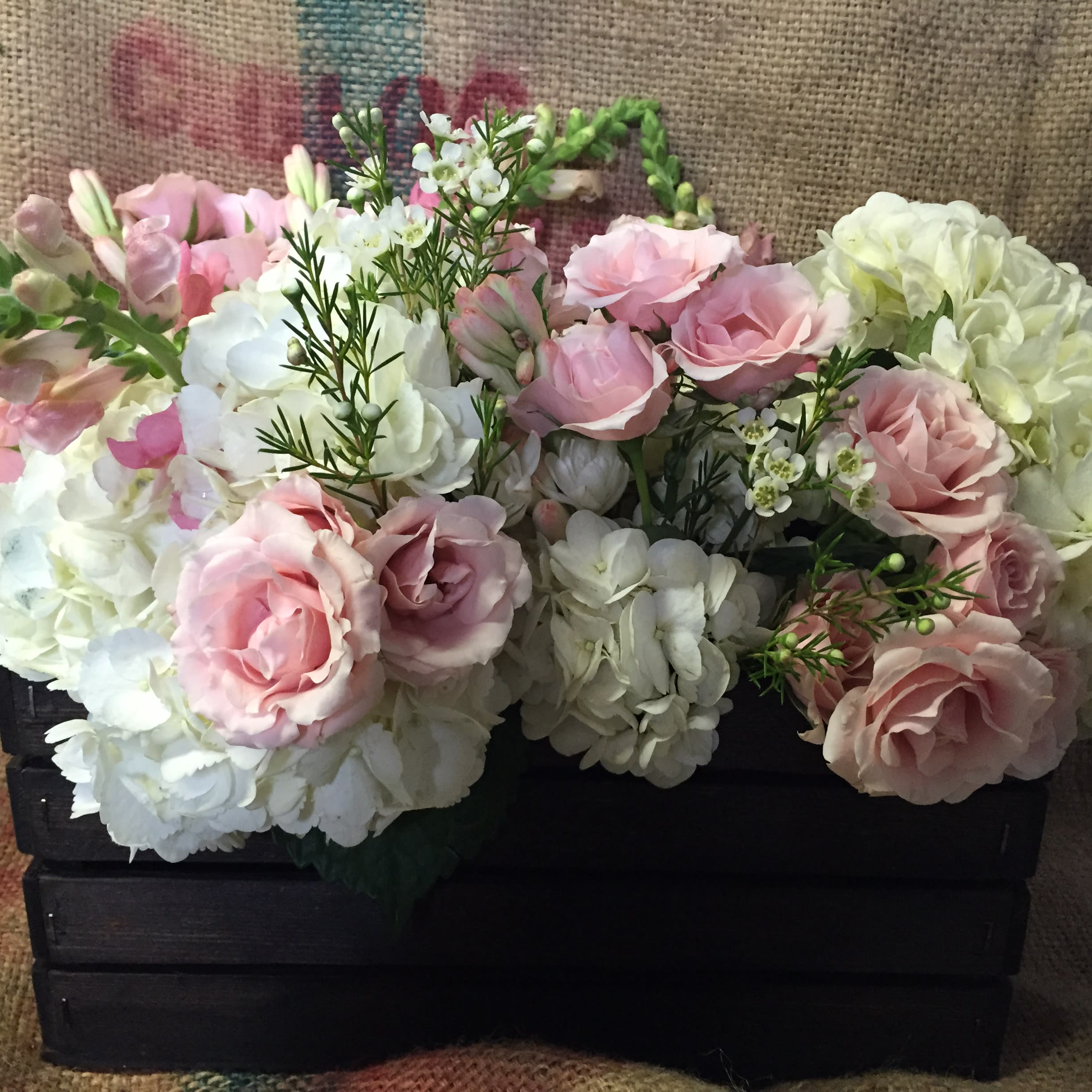 Pink and white floral arrangement in a black wooden crate