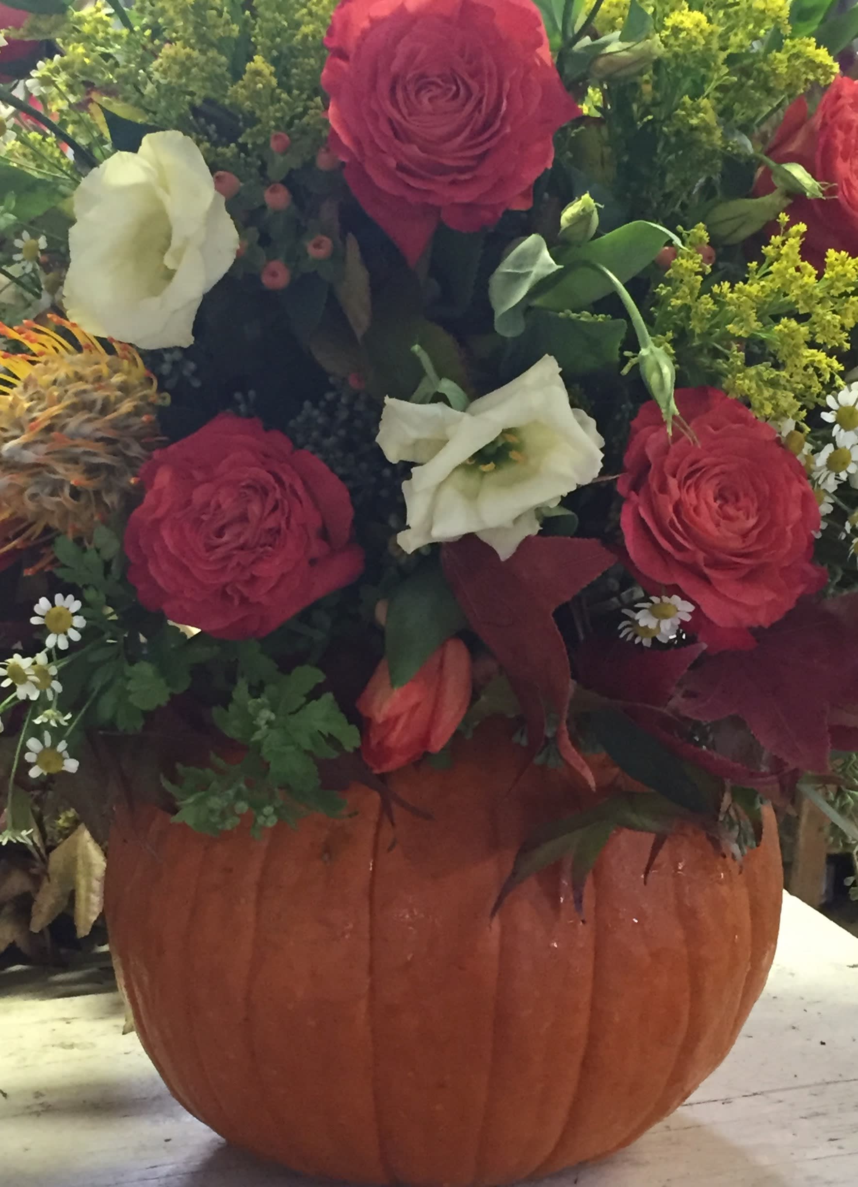 Bouquet of red and white flowers arranged in a pumpkin container