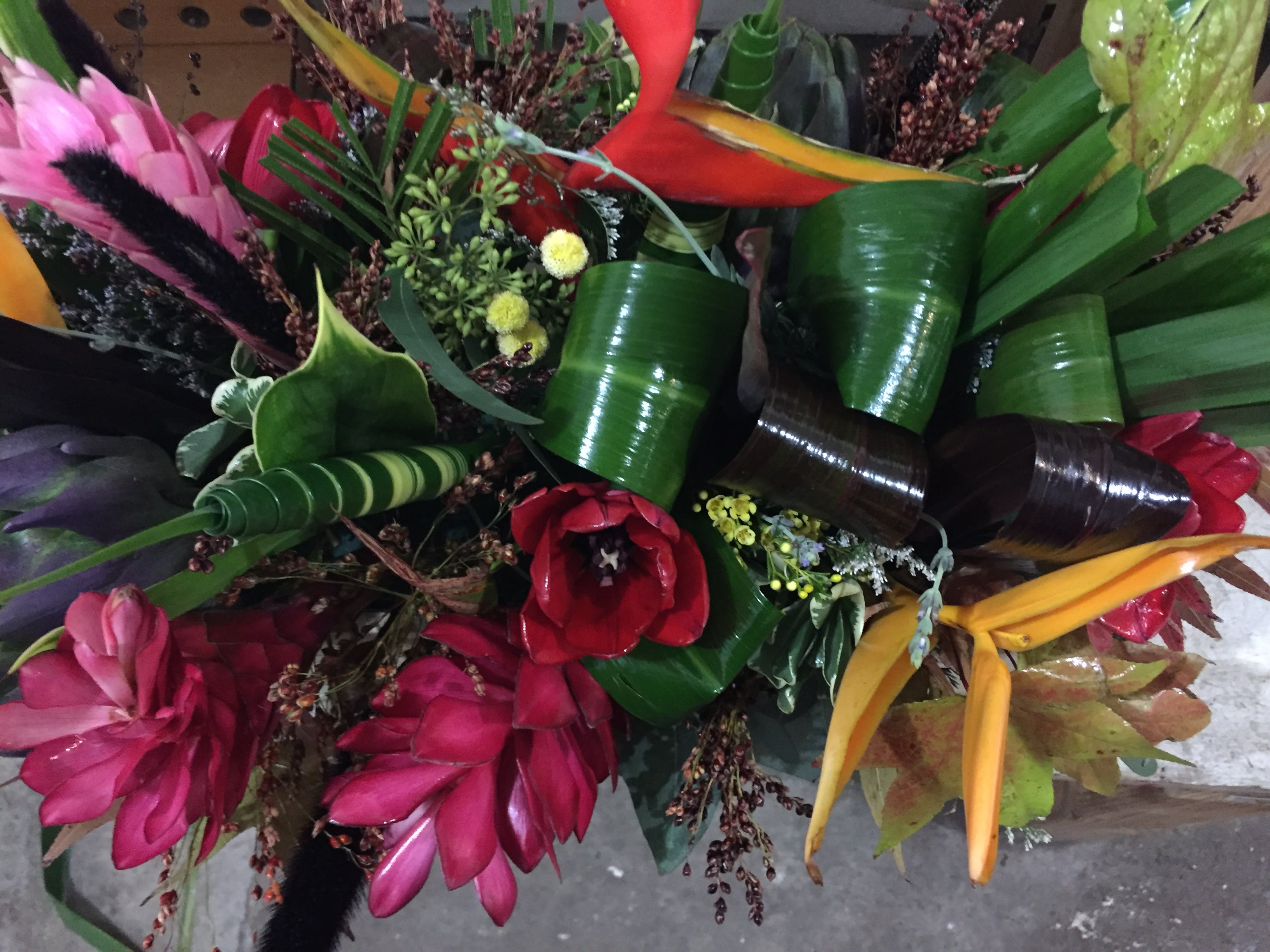 Tropical bouquet with red, pink, and yellow flowers and glossy green leaves