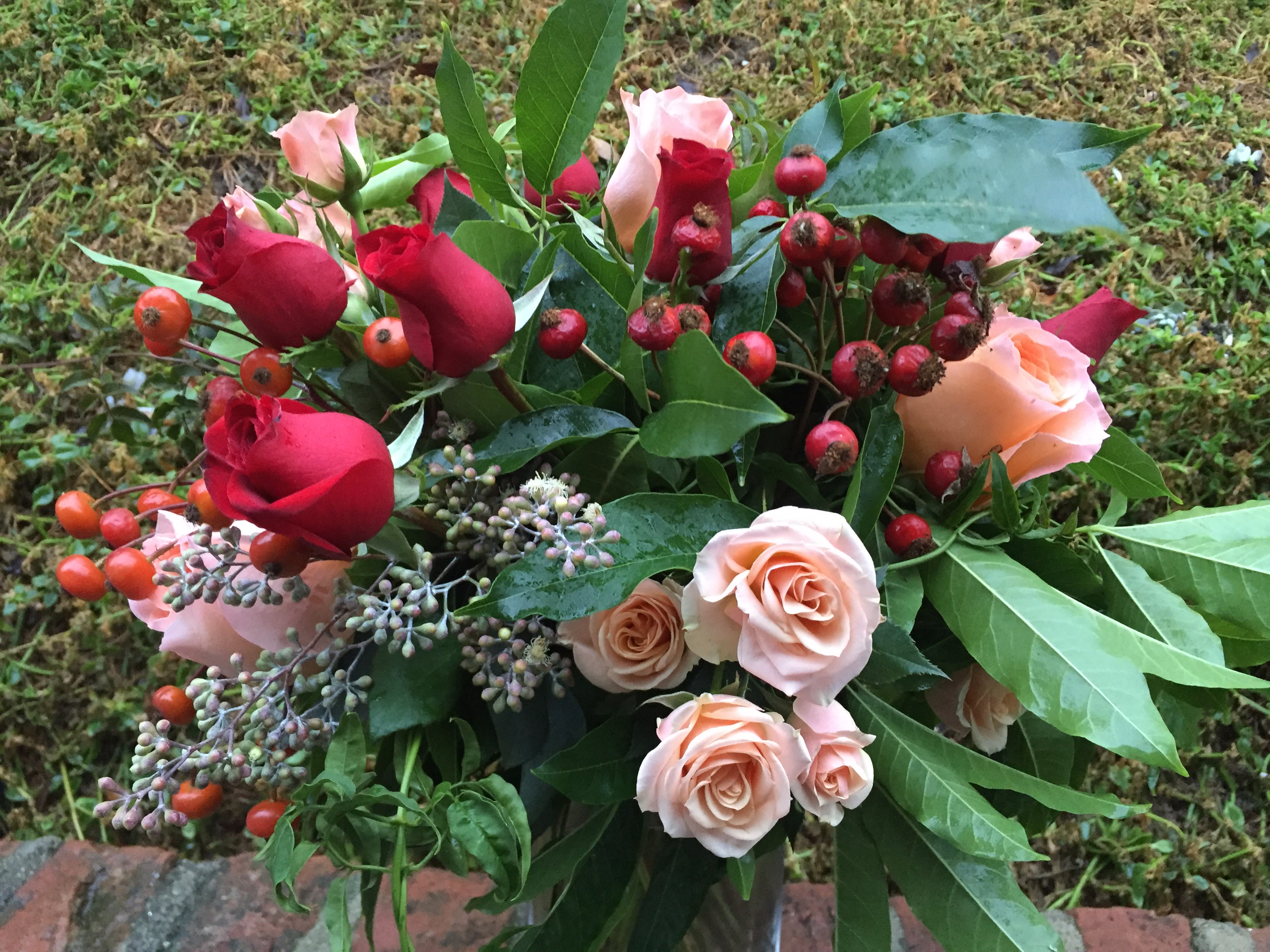 Bouquet of red and blush roses with berry accents