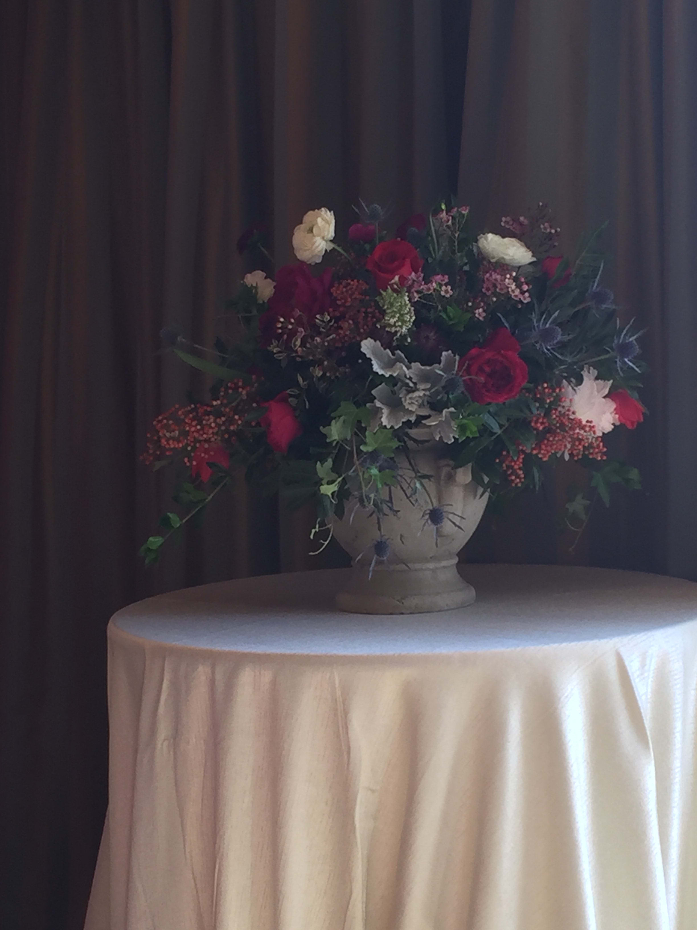 Large floral arrangement in a stone urn on a draped table