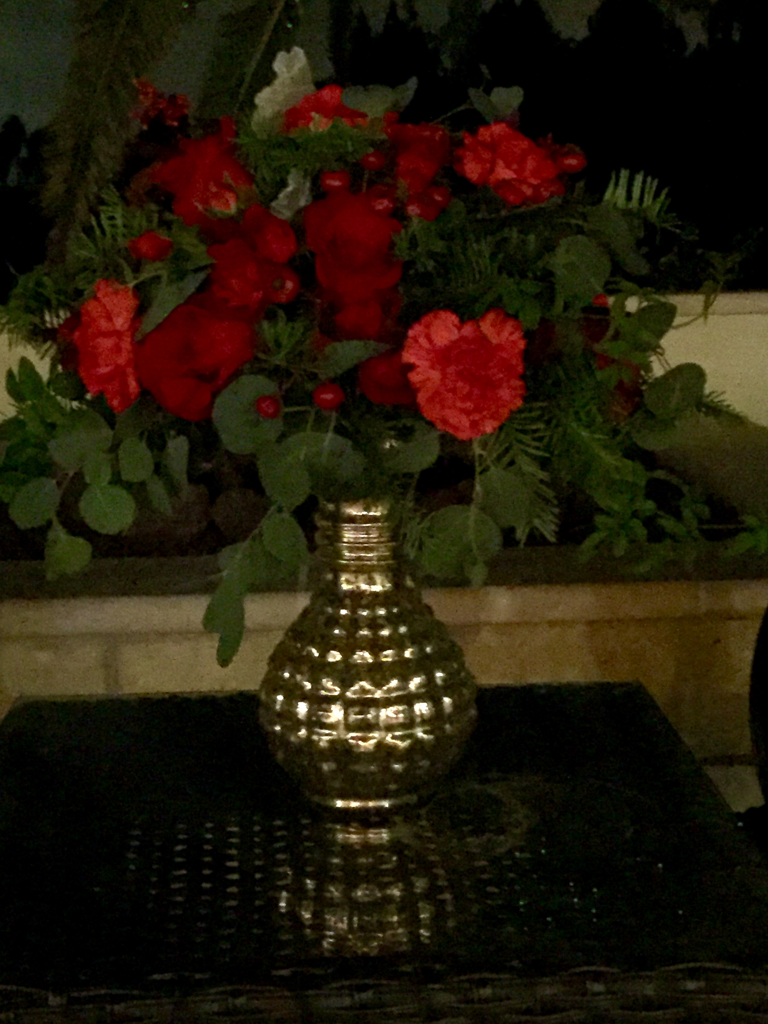 Red carnations in a gold vase with greenery