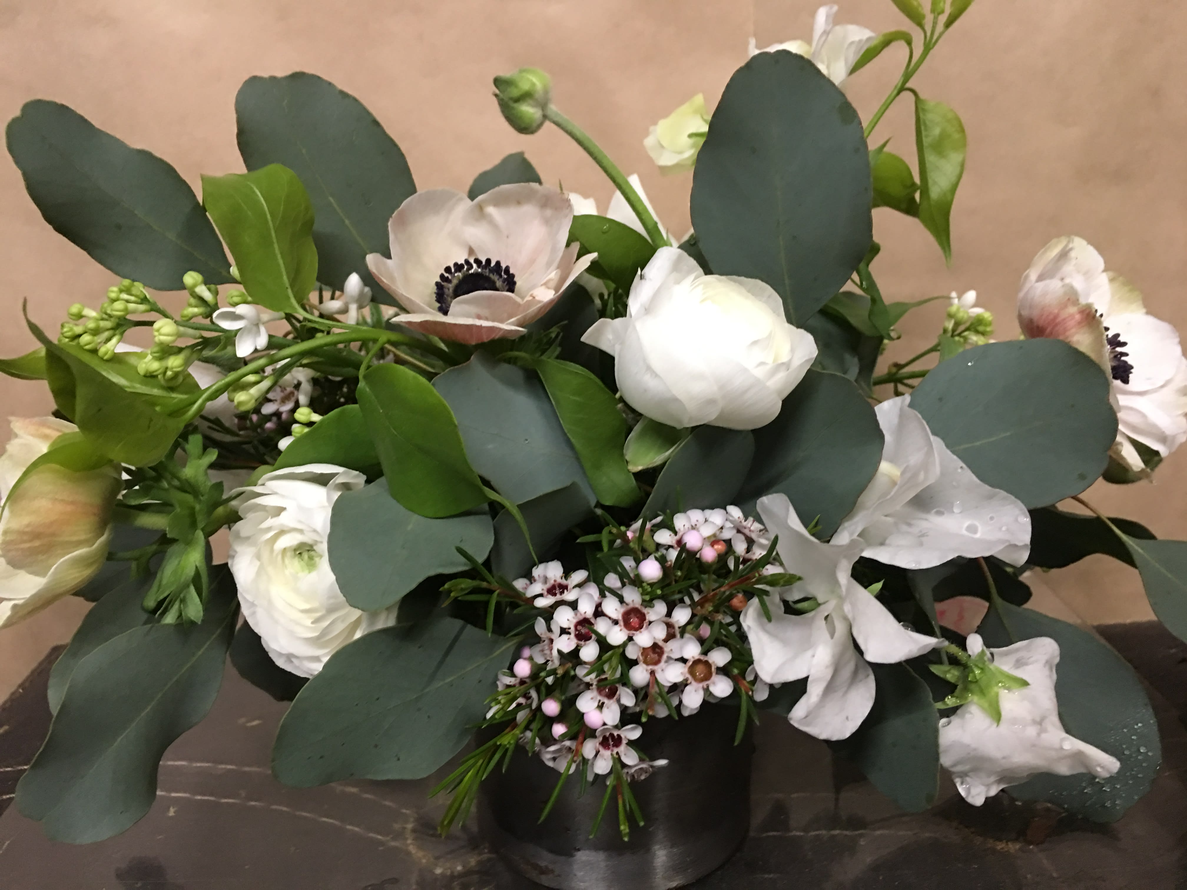 White anemones and ranunculus in a low black vase