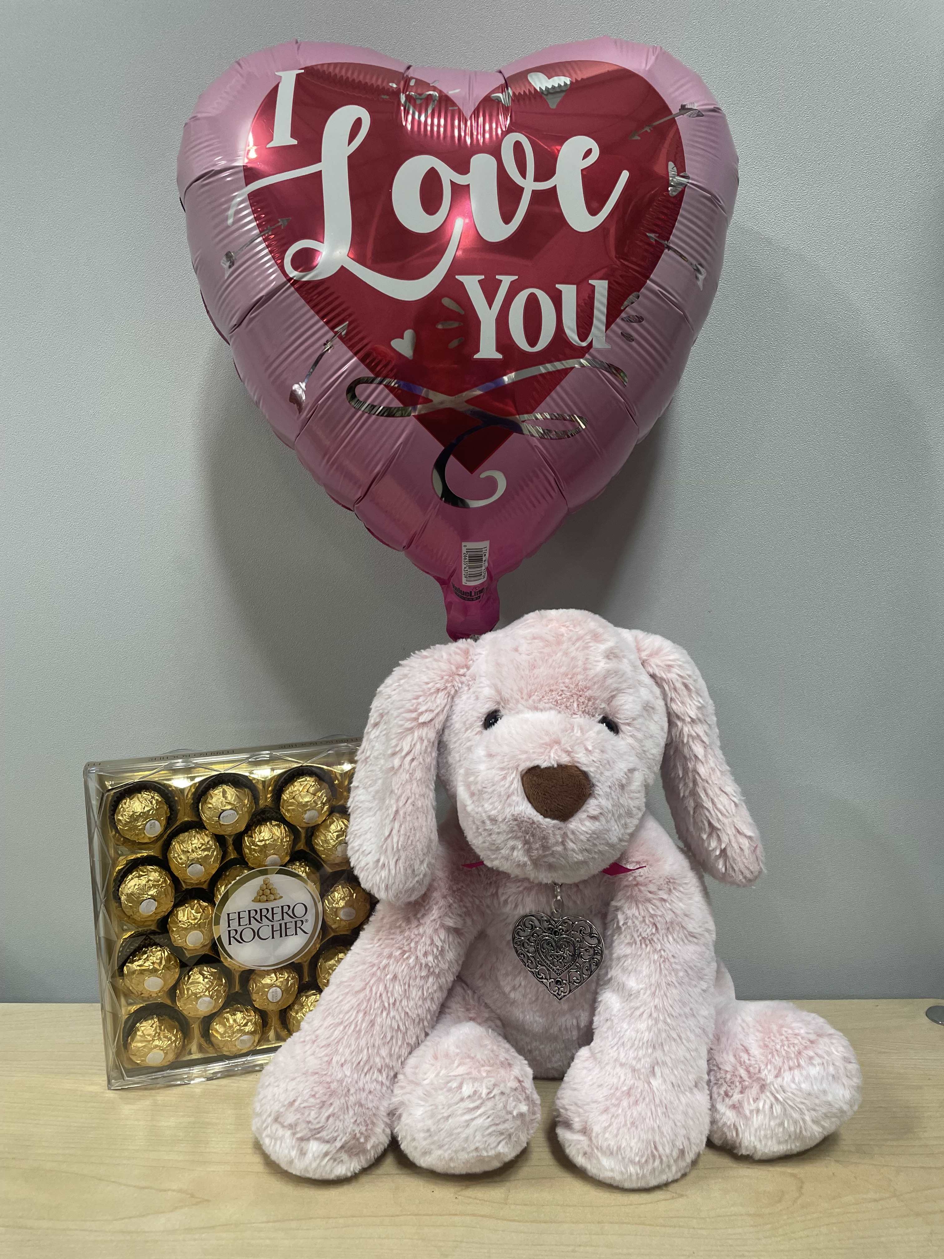 Heart-shaped "I Love You" balloon with a pink plush dog and chocolates