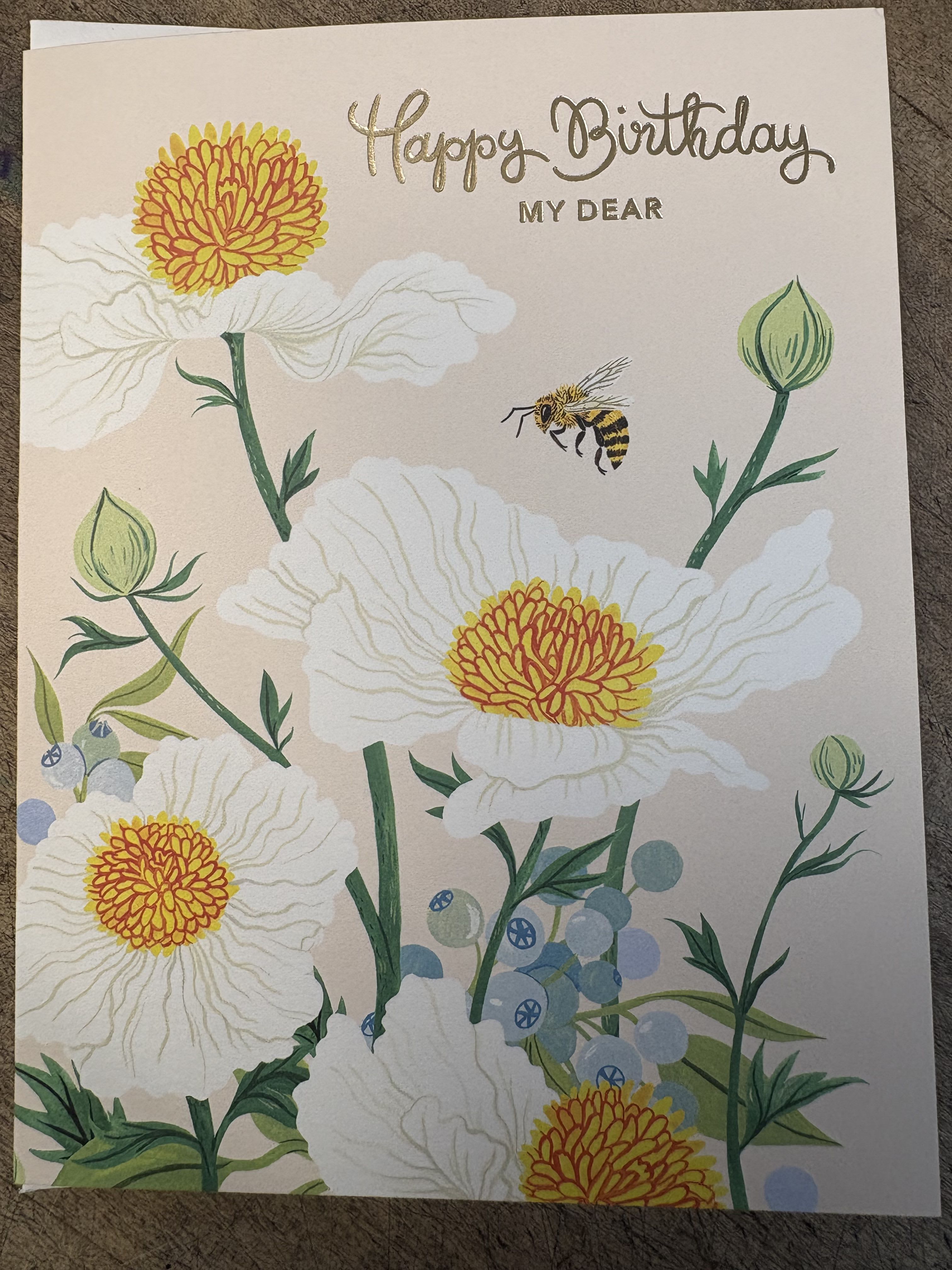 Birthday card with white flowers, a bee, and gold lettering
