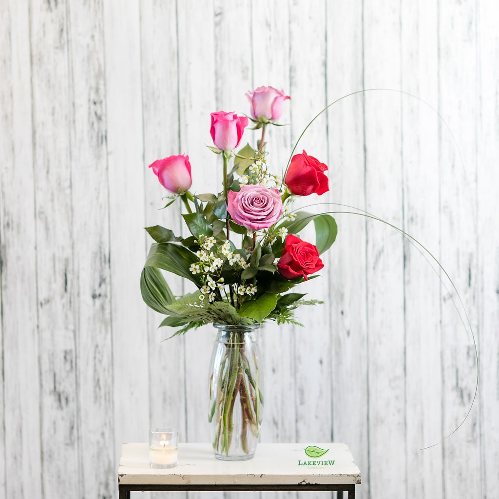 Pink and red roses arranged in a clear glass vase.