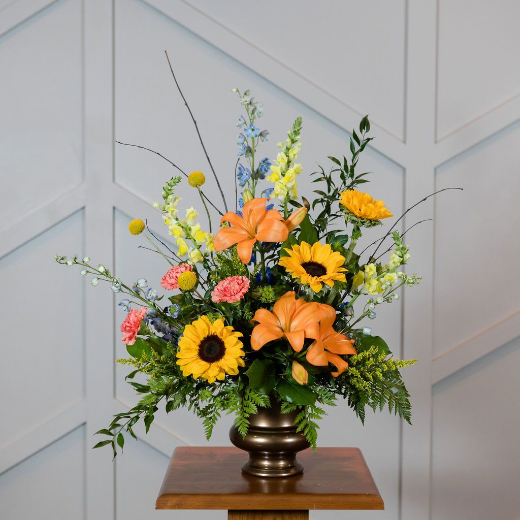 Colorful floral arrangement in a bronze vase with sunflowers and lilies