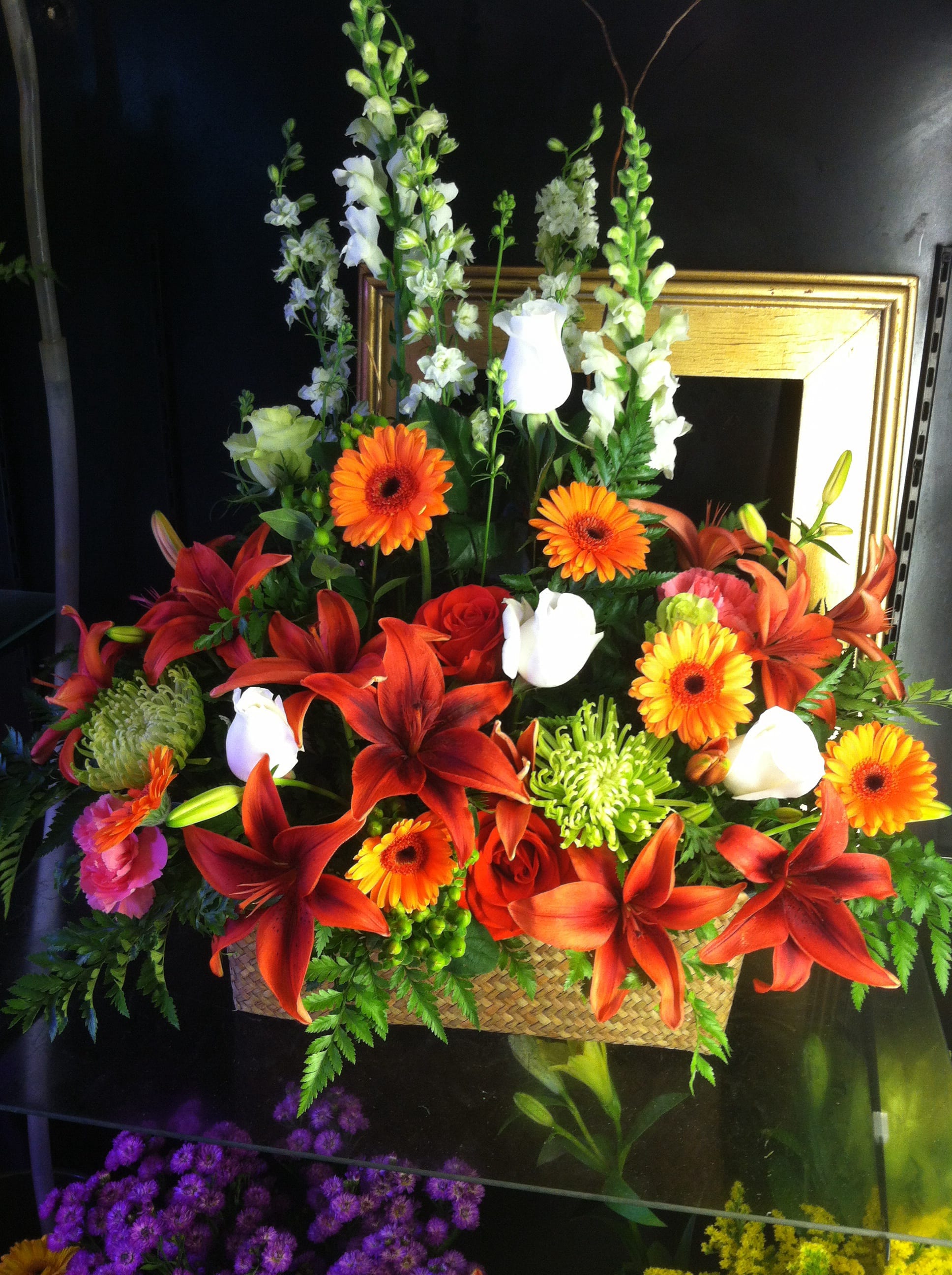 Tall basket arrangement of red lilies, orange gerberas, white callas and mixed flowers
