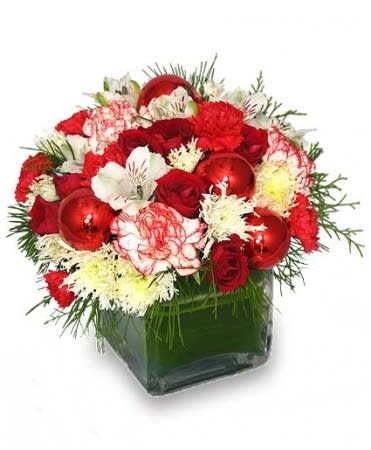 Compact red and white floral arrangement with ornaments in a clear glass cube vase