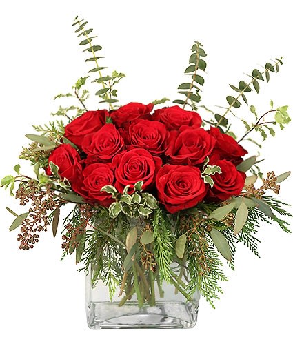 Low arrangement of red roses with assorted foliage in a square clear glass vase