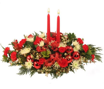 Red and white floral centerpiece with two red taper candles and shiny red ornaments.