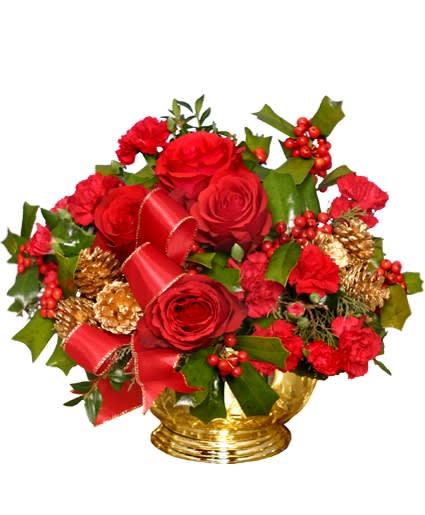 Red roses and carnations with holly, red ribbon, and gold pinecones in a gold bowl.