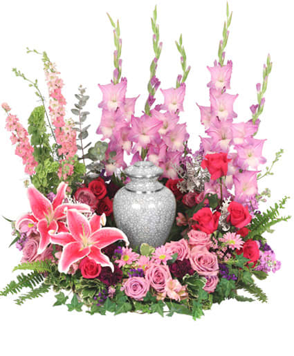 Pink and red floral arrangement encircling a gray urn with tall pink blooms at the back