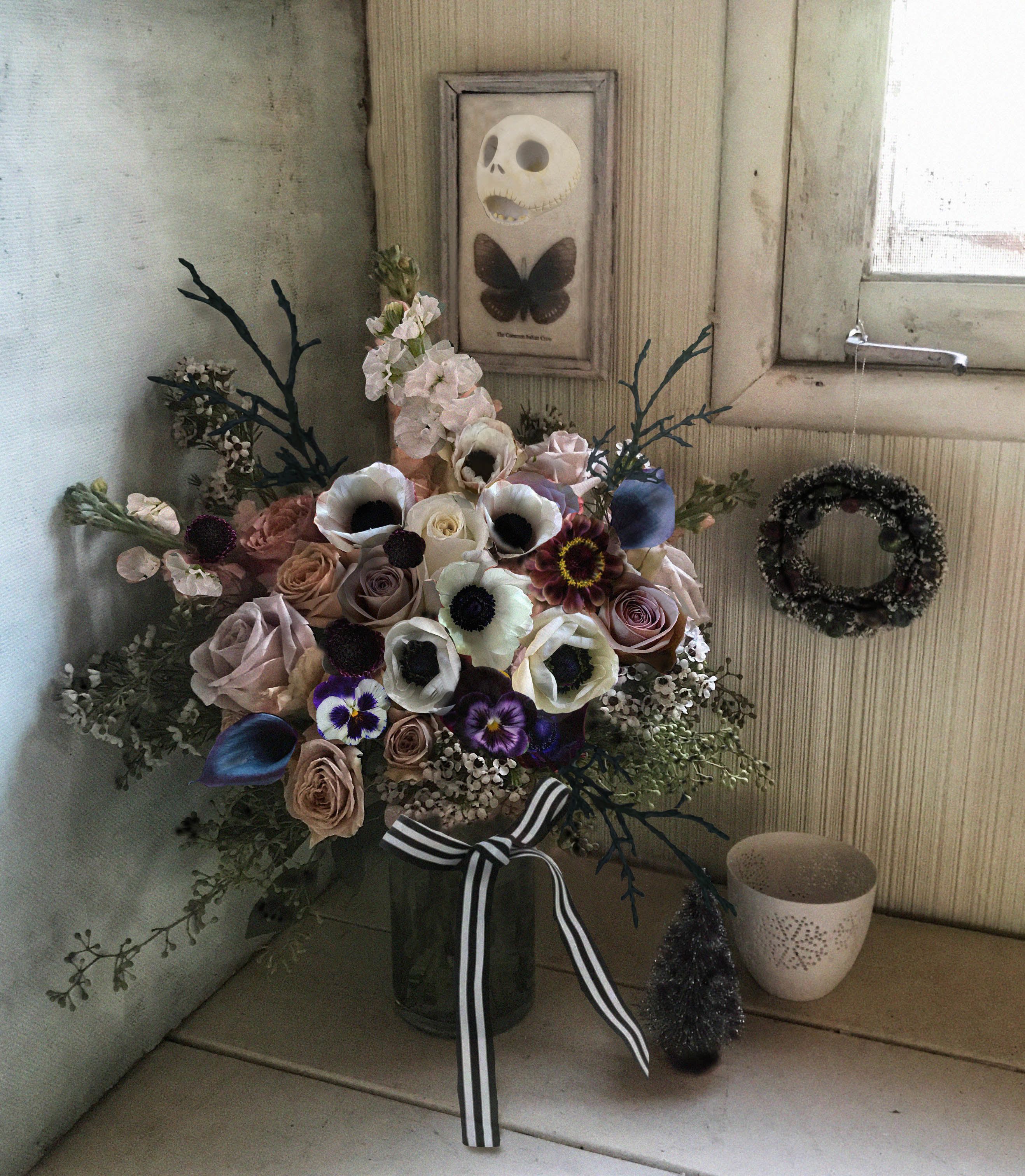Mixed bouquet in a glass vase with roses, anemones, and dark accents