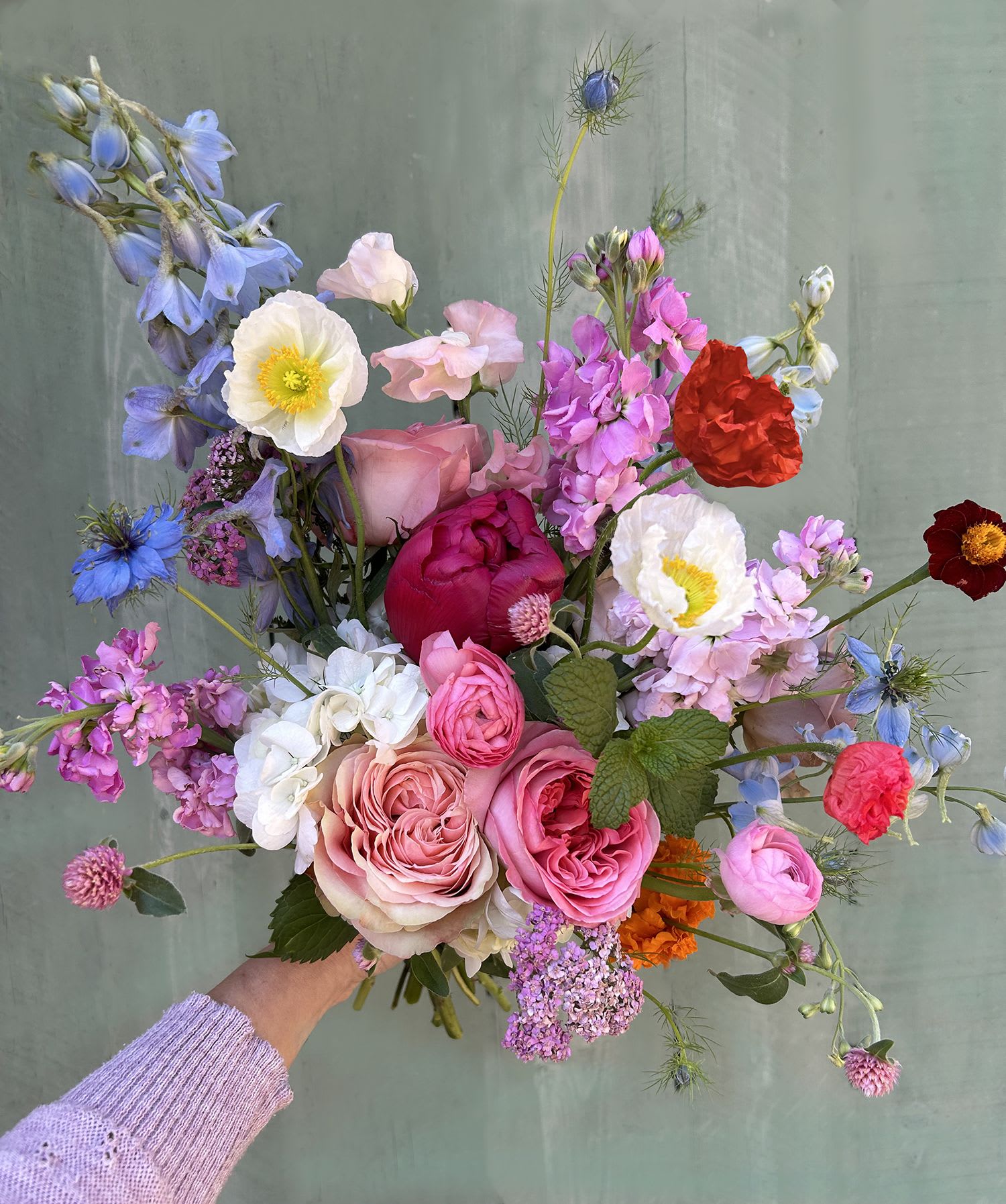 Handheld bouquet of pink, blue, and white mixed flowers