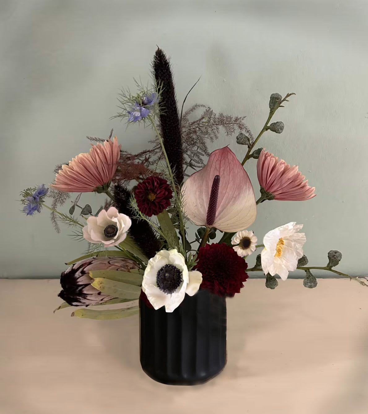 Skellington - A lovely spooky wild arrangement in a black relief vase. Perfect for Halloween and Day of the Dead season - available for hand delivery in LA. The arrangement is a mix of stems like anemones, chrysanthemums, poppies, alturium - or other seasonal stems with similar spooky vibes.