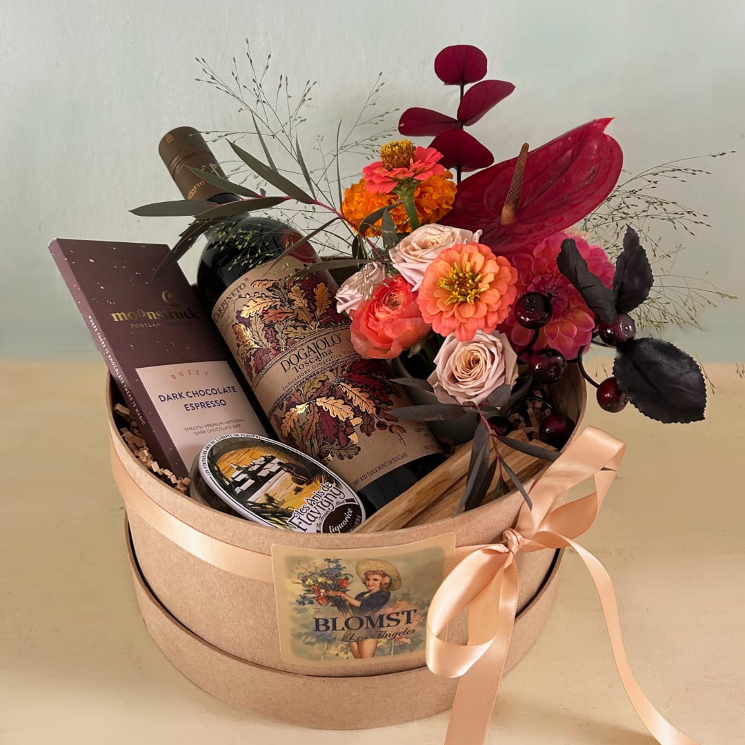 Gift box with flowers, wine, chocolate, and a small tin of treats
